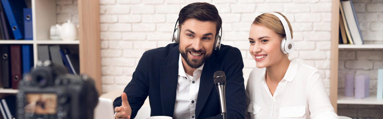 A man and a women podcasting and smiling