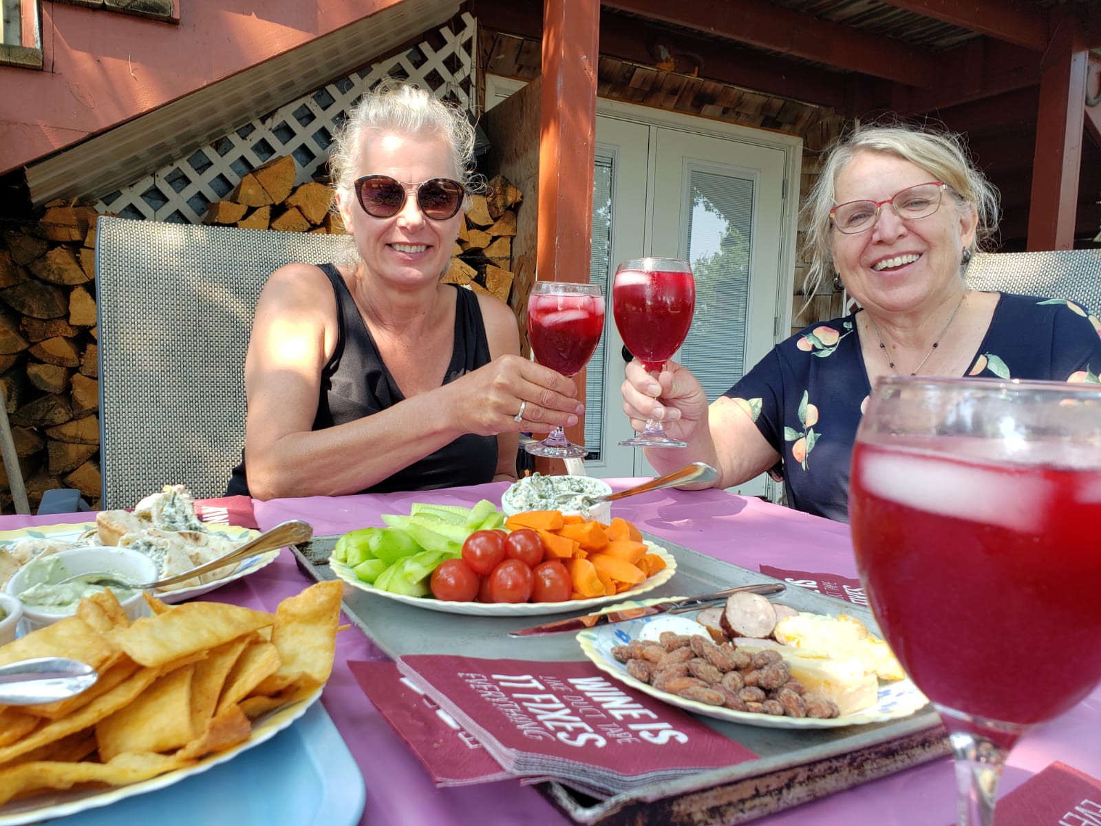 Two ladies toasting with wine glasses with delicious food in front of them