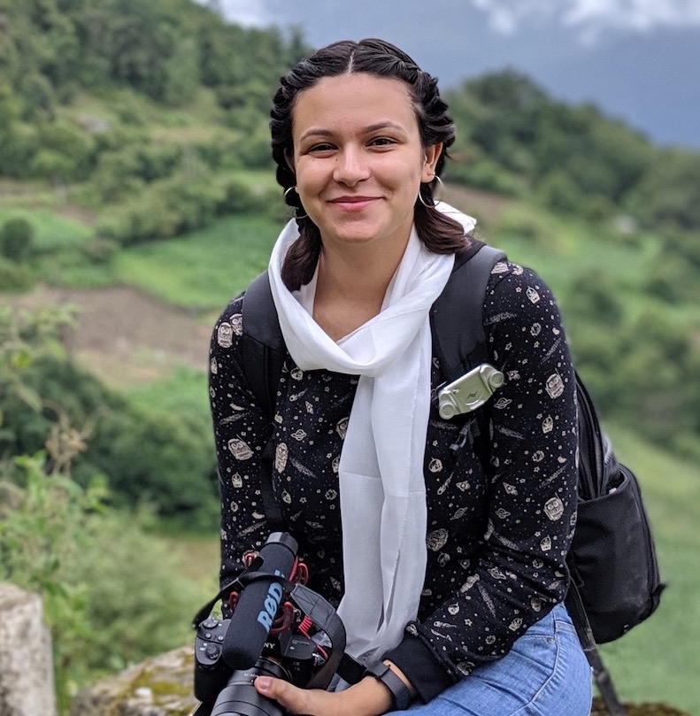 A photo of Isha, sitting on a rock with the backdrop of Arunachal Pradesh's mountains