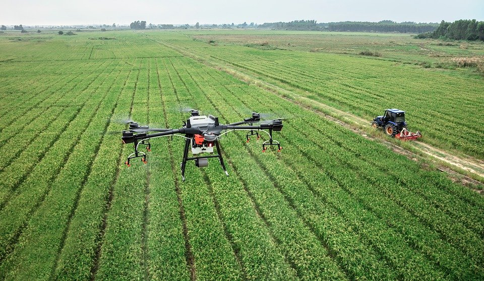 Drone surveying farmland and tractor