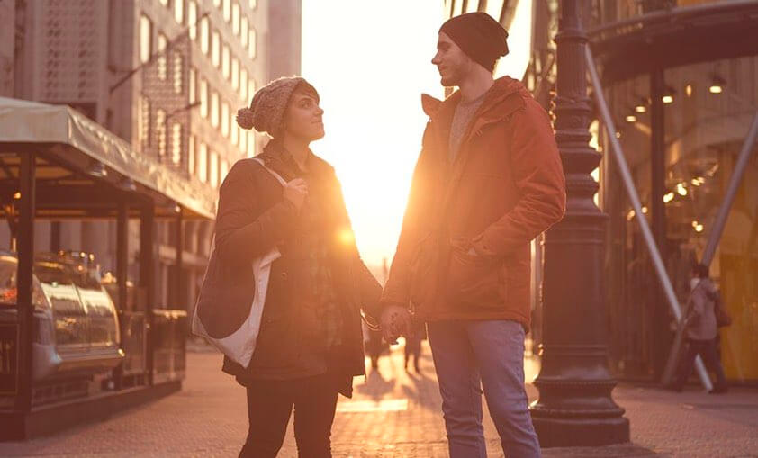 Couple holding hands, looking at each other in a street