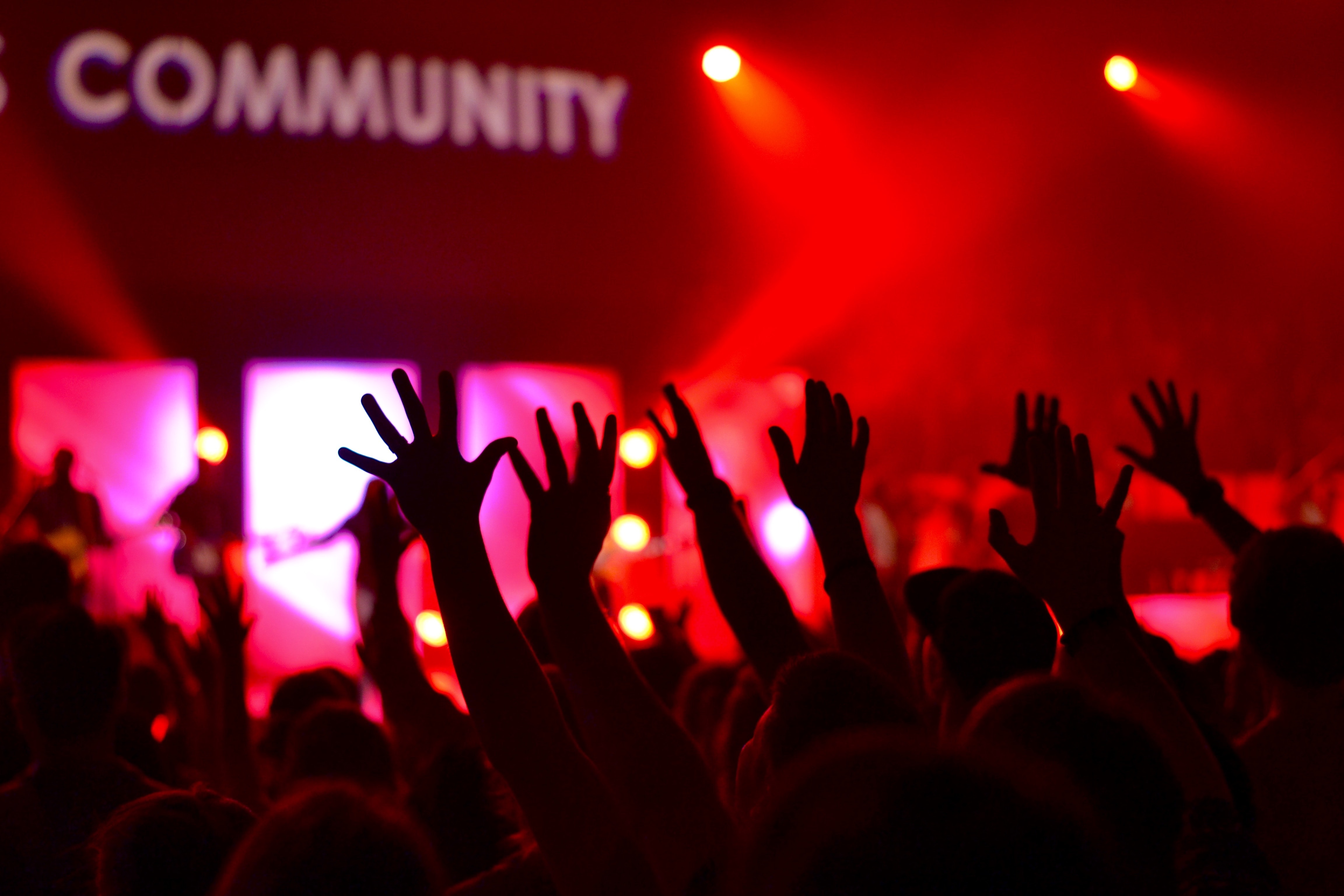 A picture of many people raising their hands with a community sign showing