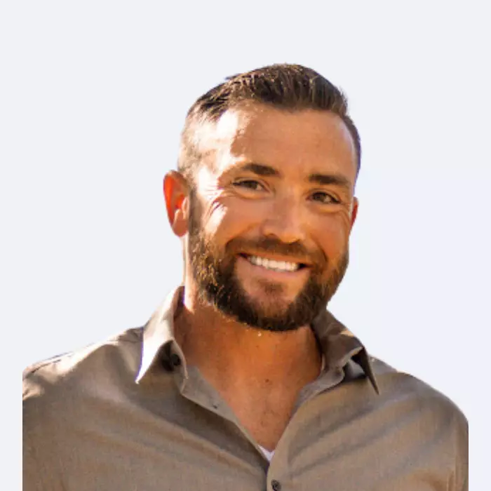 Man smiling at the camera with gray button down shirt