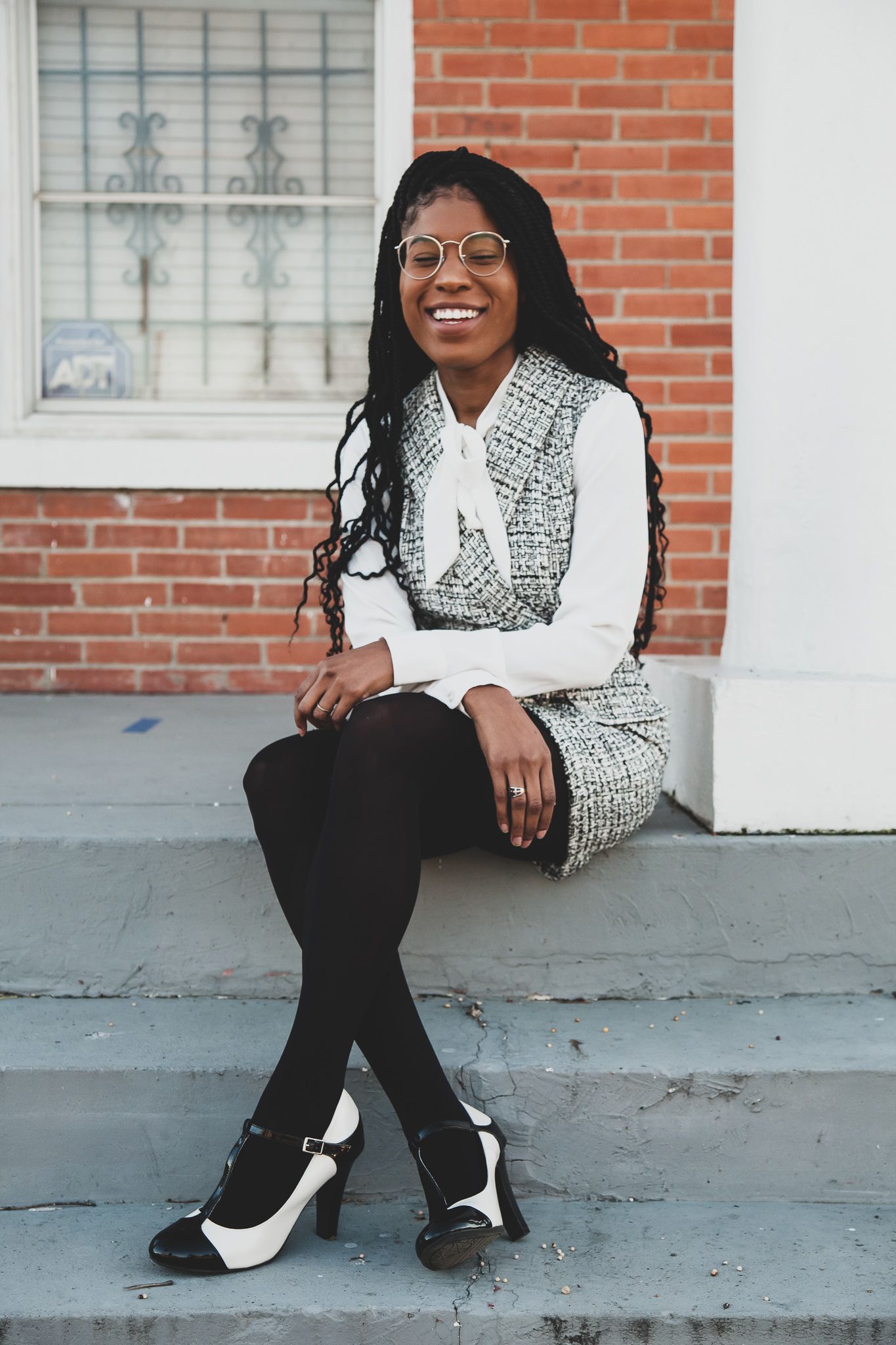 Jessica Mason smiling and sitting down on steps in front of brick building