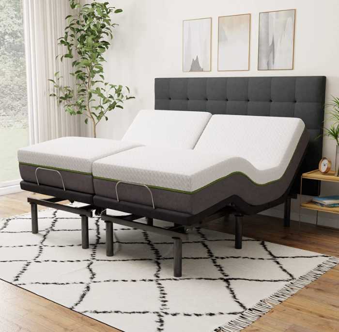 An upholstered black adjustable bed frame with mattresses on top on a rug in a bedroom