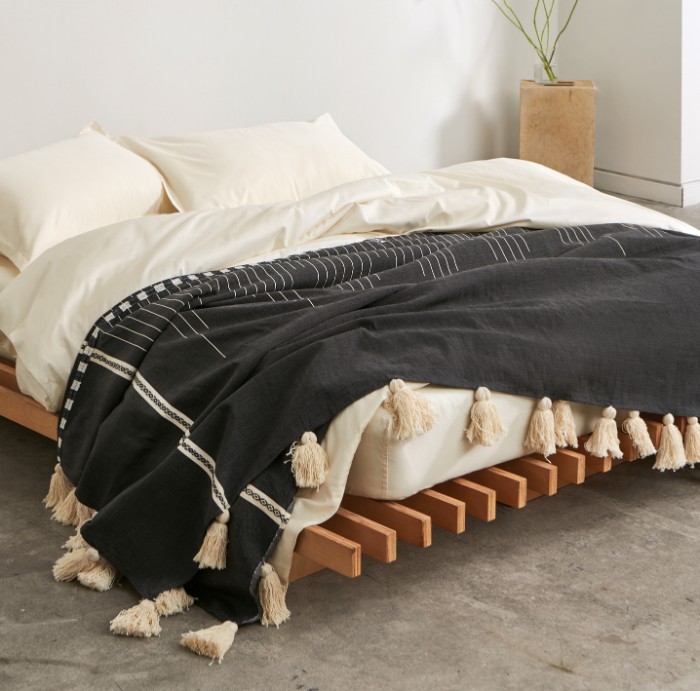 The No Fuss Plus bed frame from Quagga Designs with a mattress and bedding on top in a bright bedroom with concrete floor