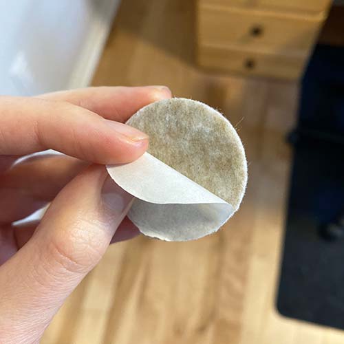Someone peeling the back of a felt pad