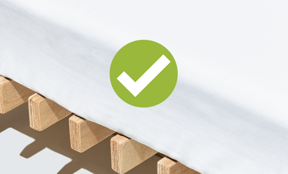 Bed slats with a white mattress on top of it and a green checkmark graphic.
