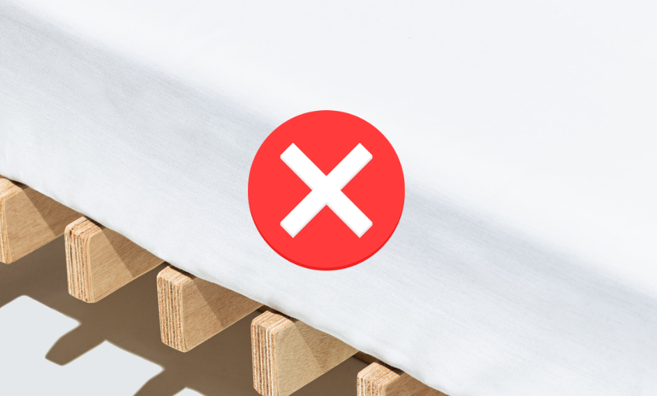 Bed slats with a white mattress on top of it and a red X graphic.