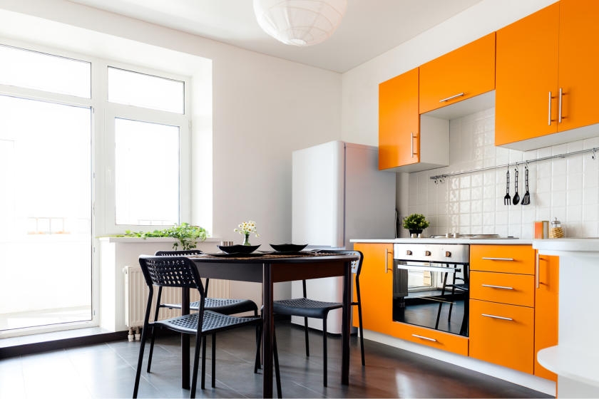 White kitchen and dining room with bright, orange cabinets