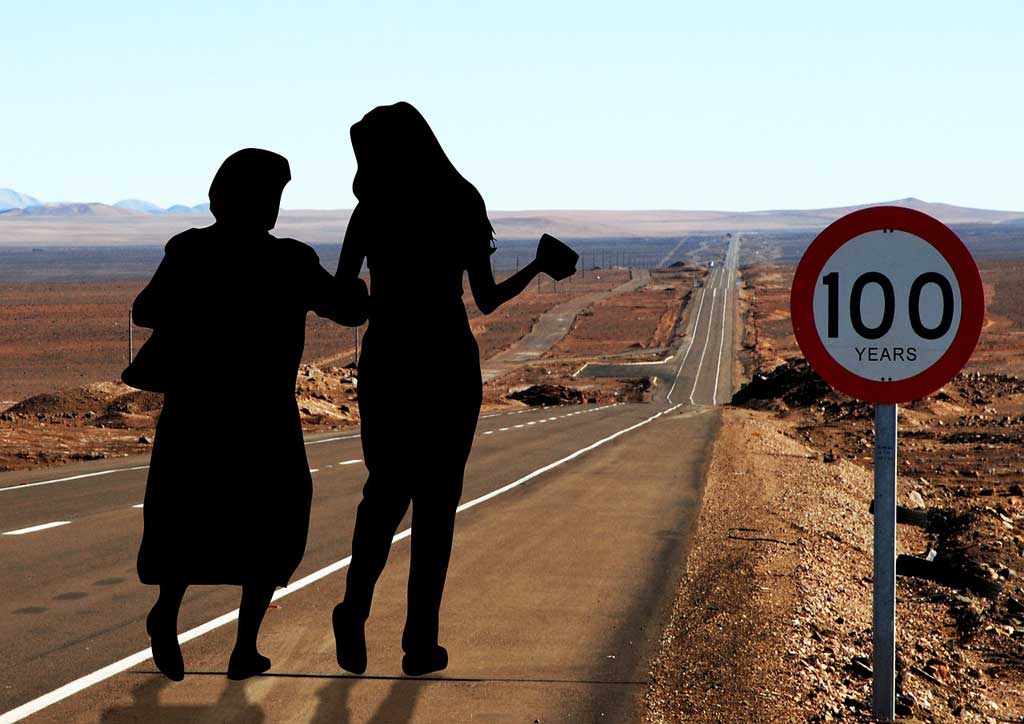 Altenpflege: Zwei Frauen auf der Straße mit Verkehrschild 100 Jahre