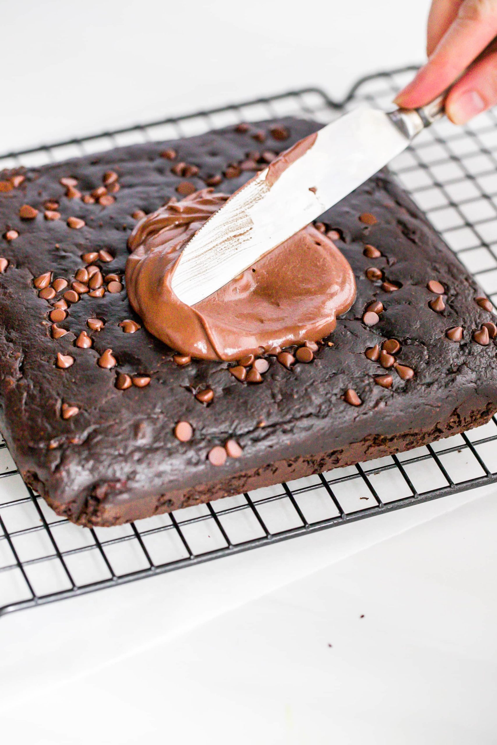 chocolate frosting being added to the cake