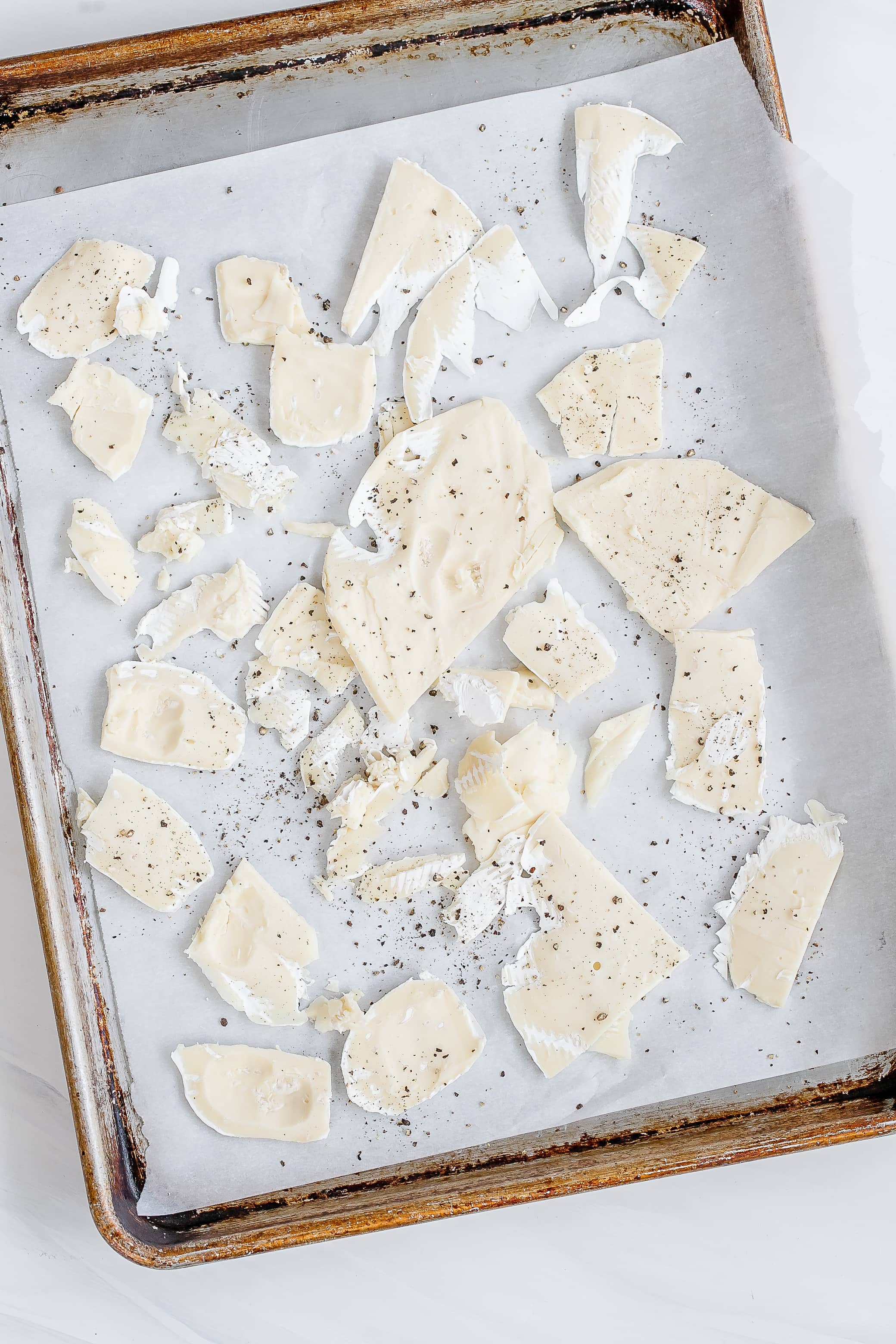 brie rinds on baking sheet with pepper. 
