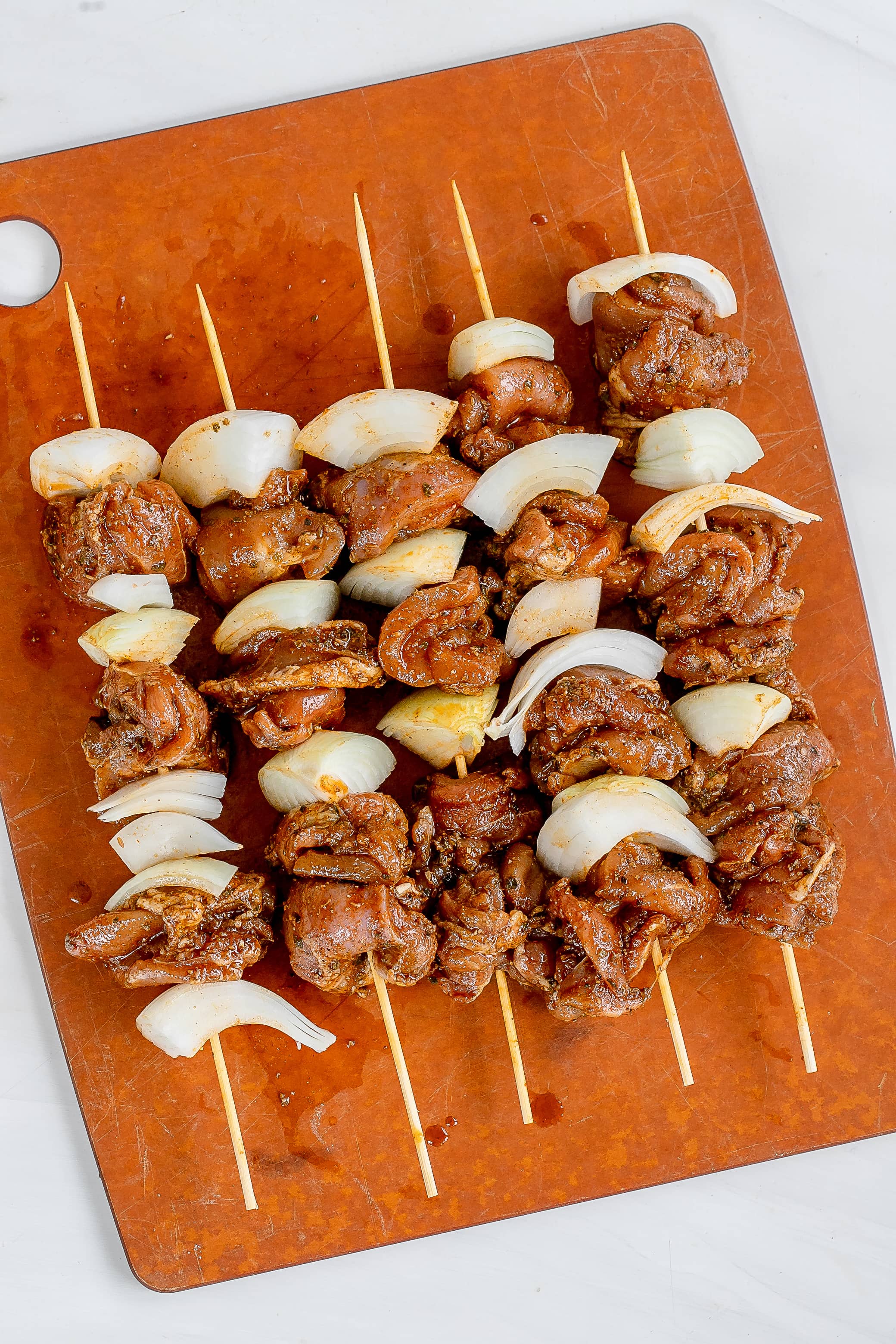 chicken skewers on cutting board.
