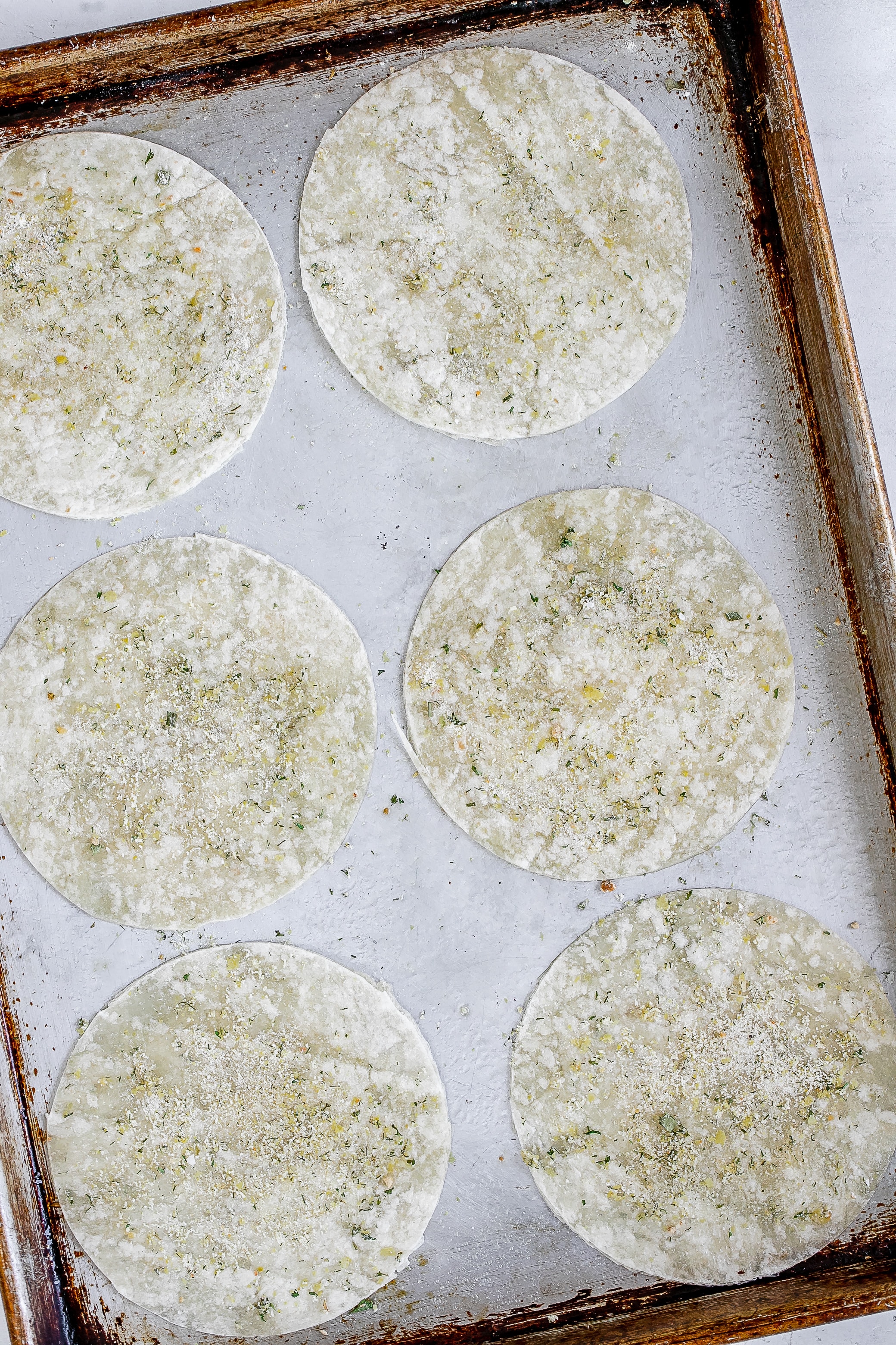 tortilas with seasoning on baking sheet.