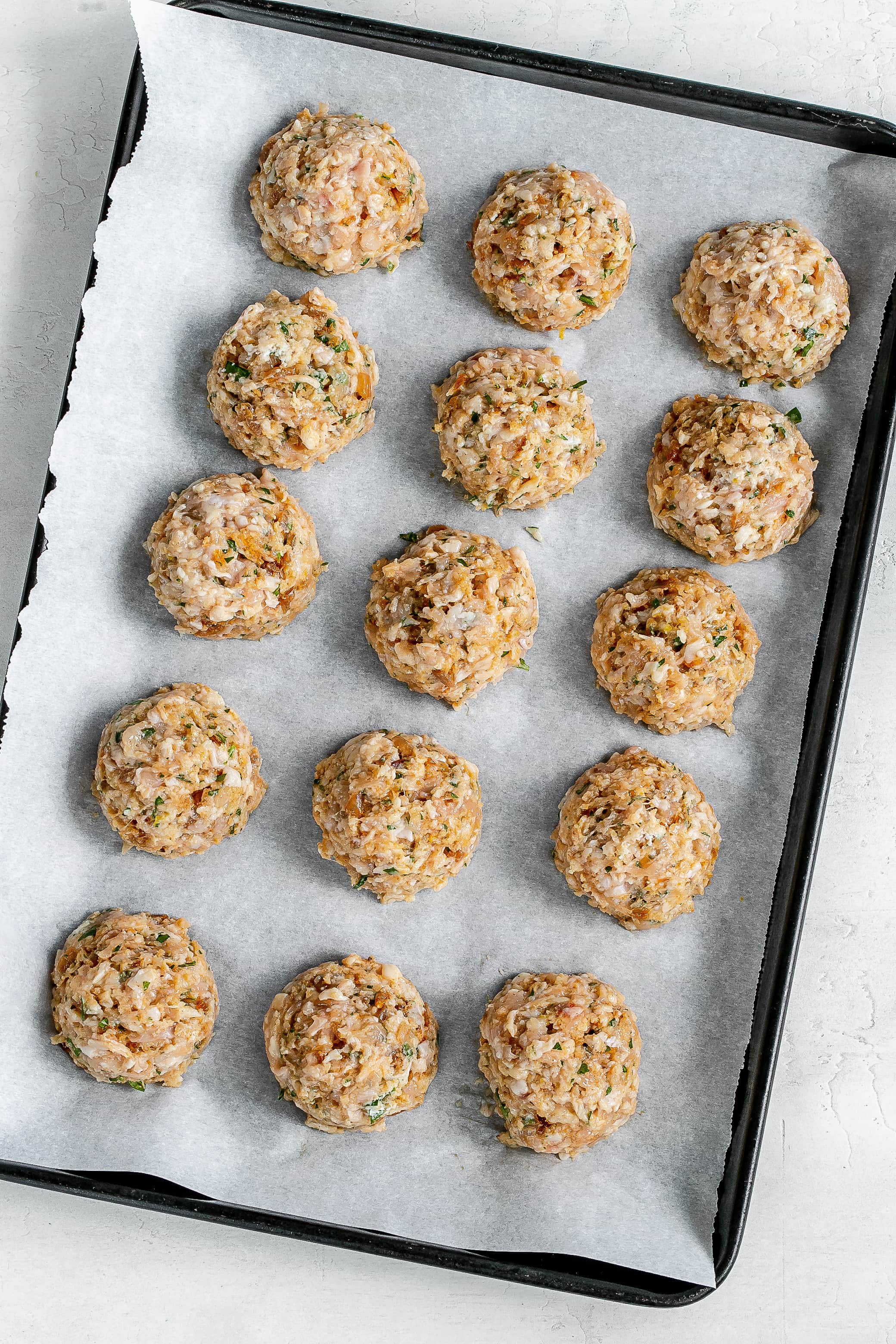 chicken formed into meatballs on a baking sheet.