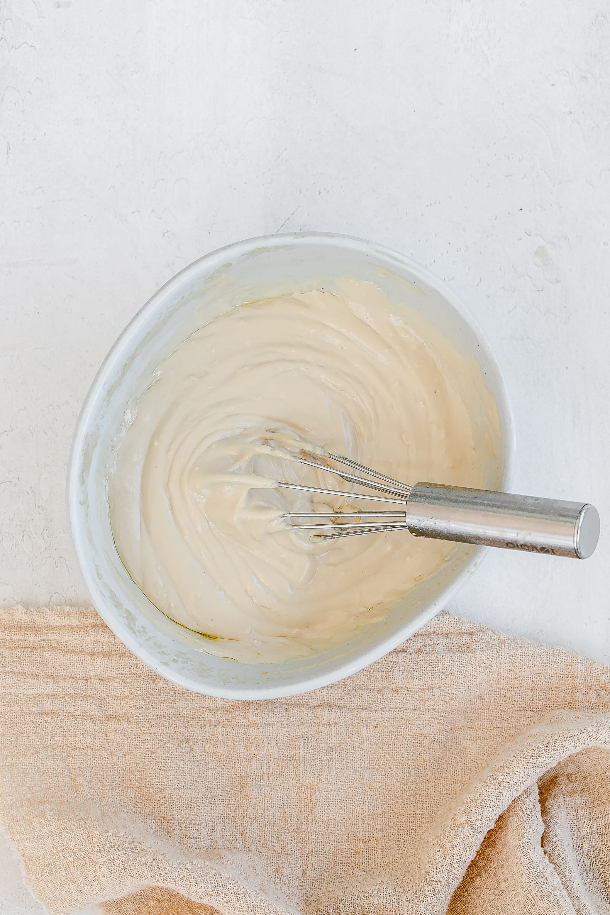 tahini mixture in bowl with whisk.