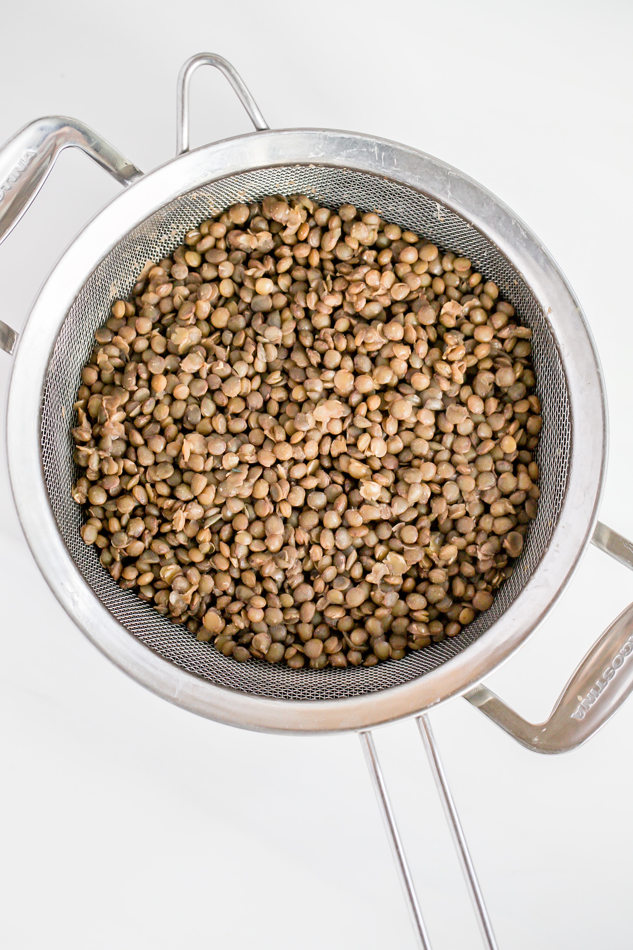 lentils sitting in a sieve over a pot. 