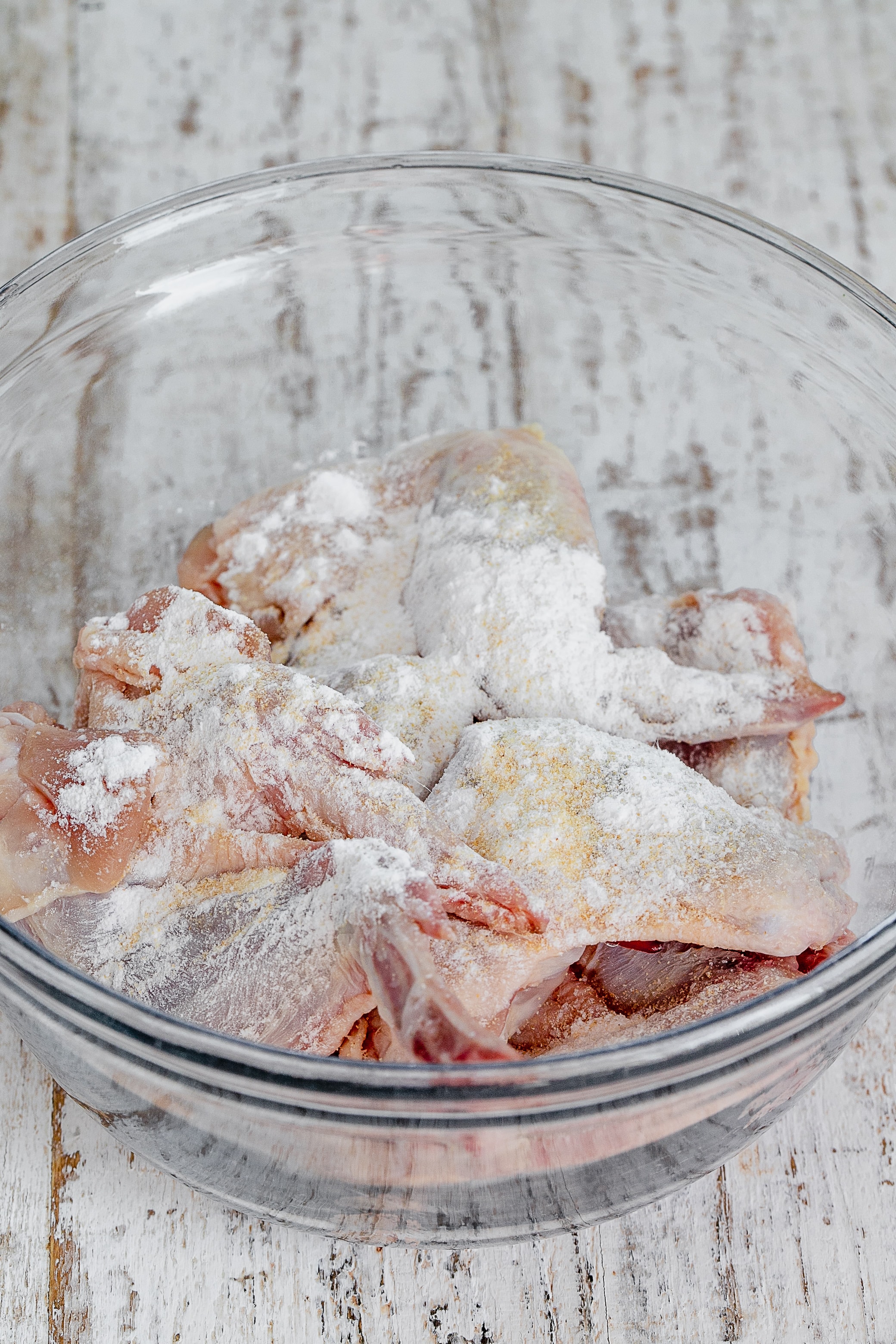 chicken wings in a bowl with seasoning.