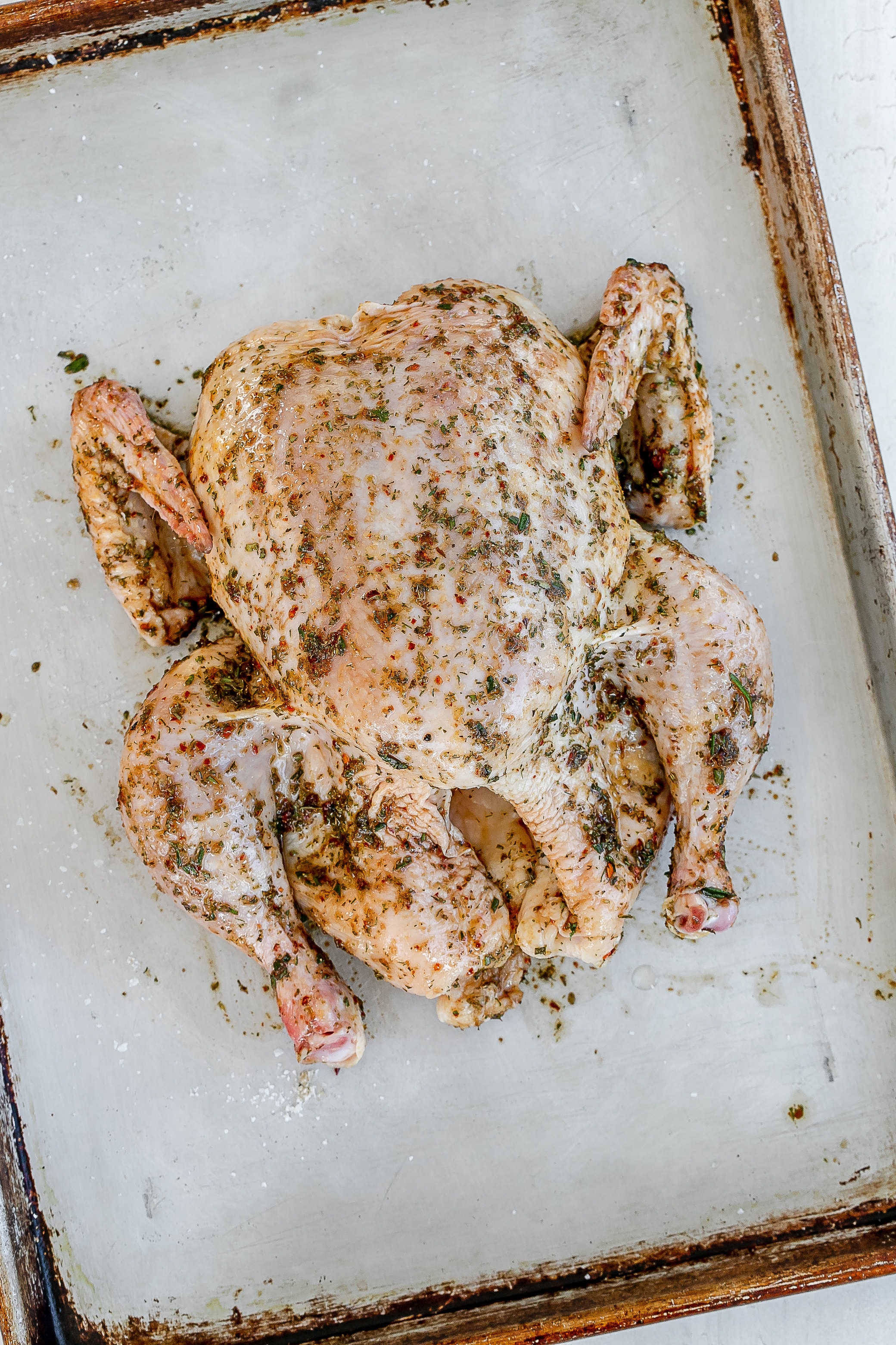 raw whole chicken with oil and spices on it. 