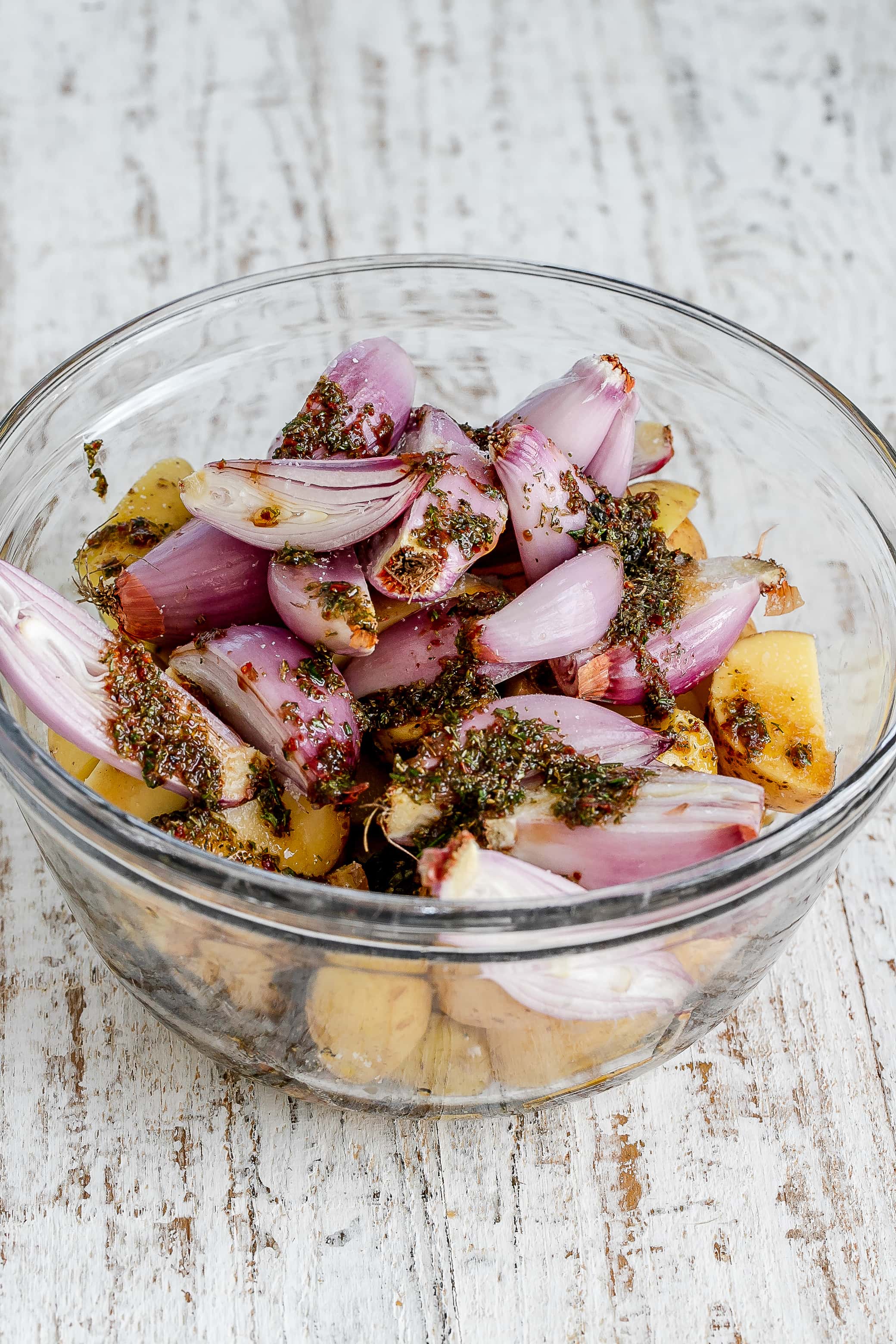 veggies in bowl tossed in oil and spices. 