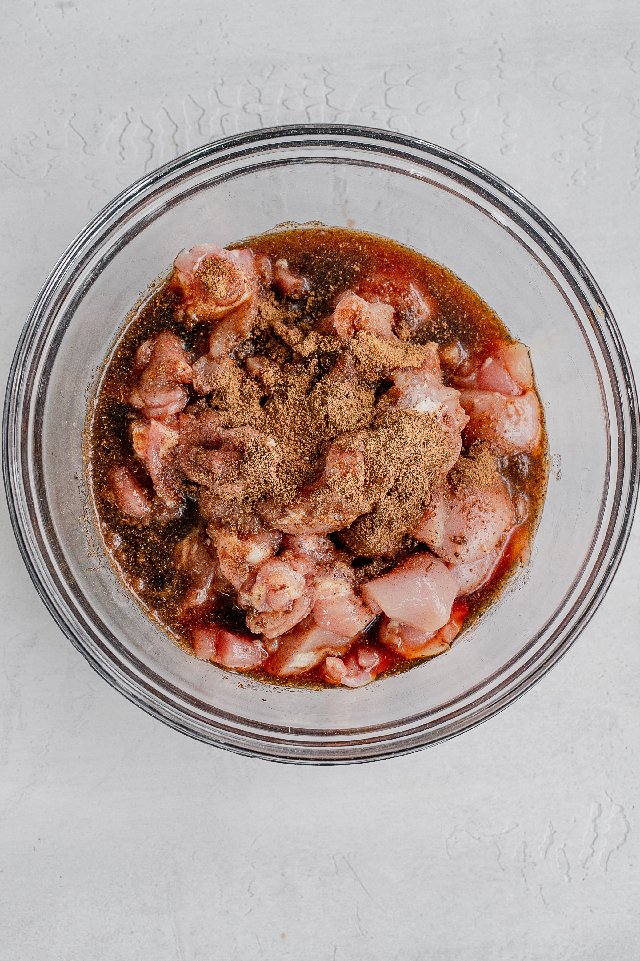 diced chicken thigh in bowl with marinade.