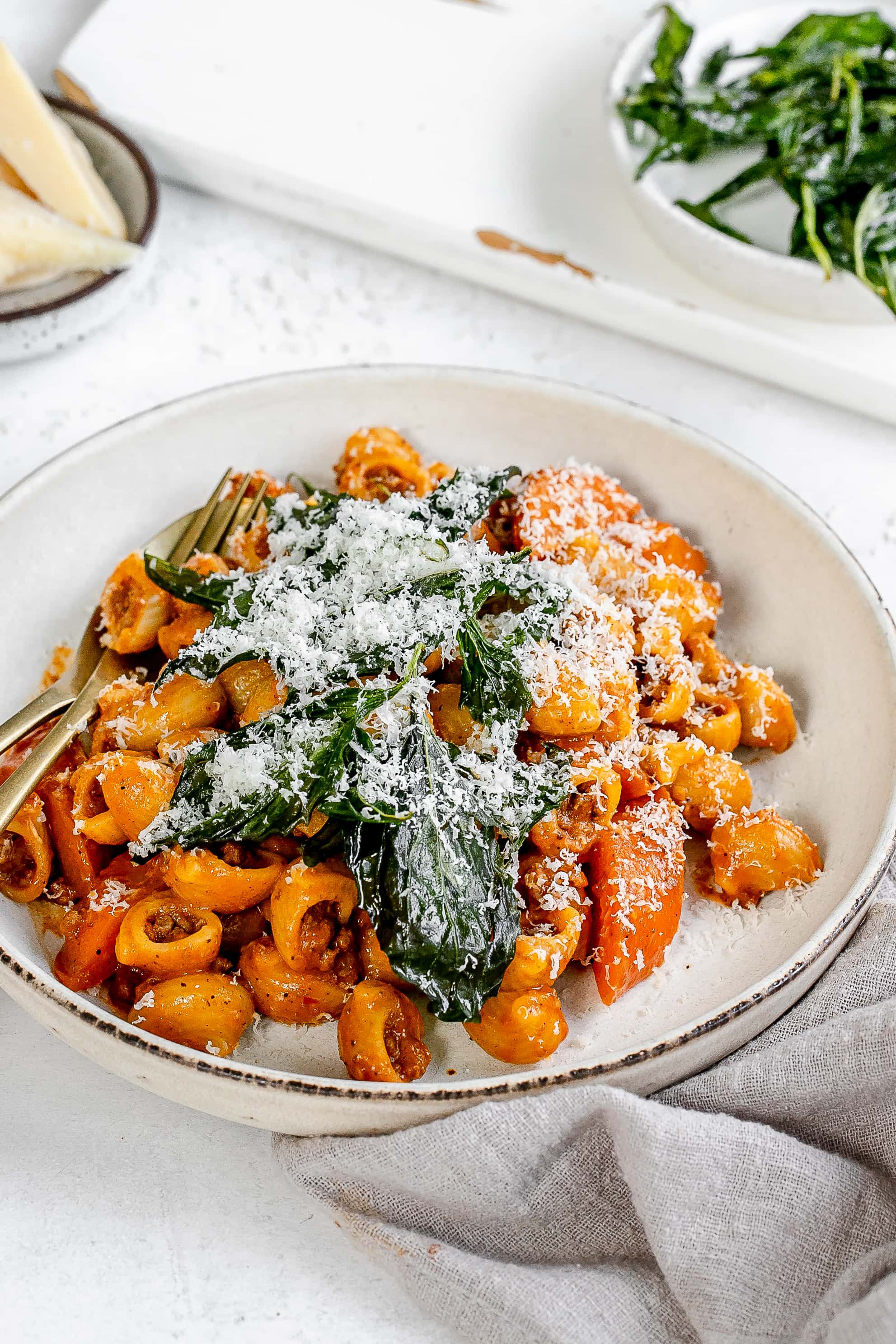 Thai bolognese on a plate topped with cheese and basil.