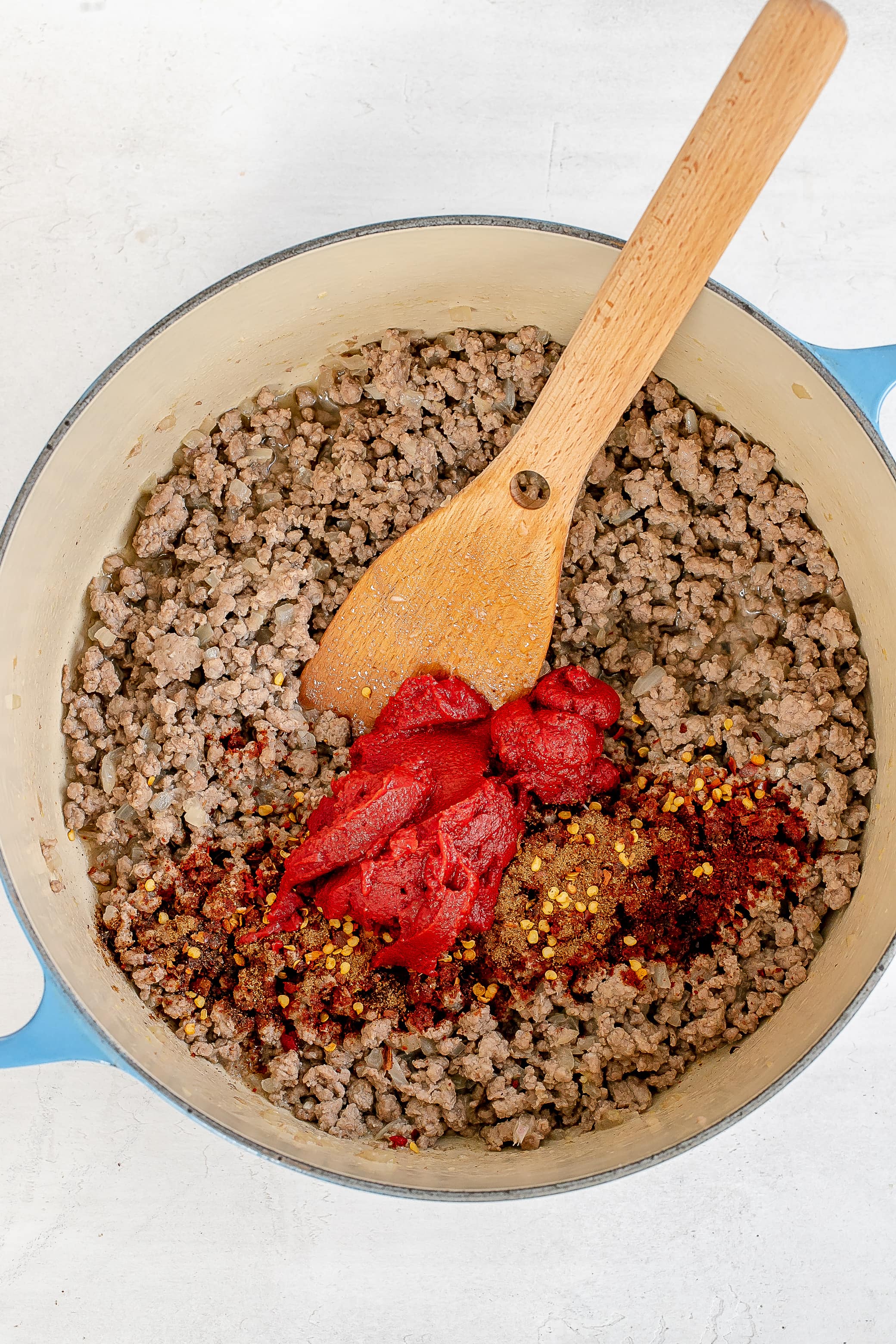 ground beef with spices and tomato paste in dutch oven.
