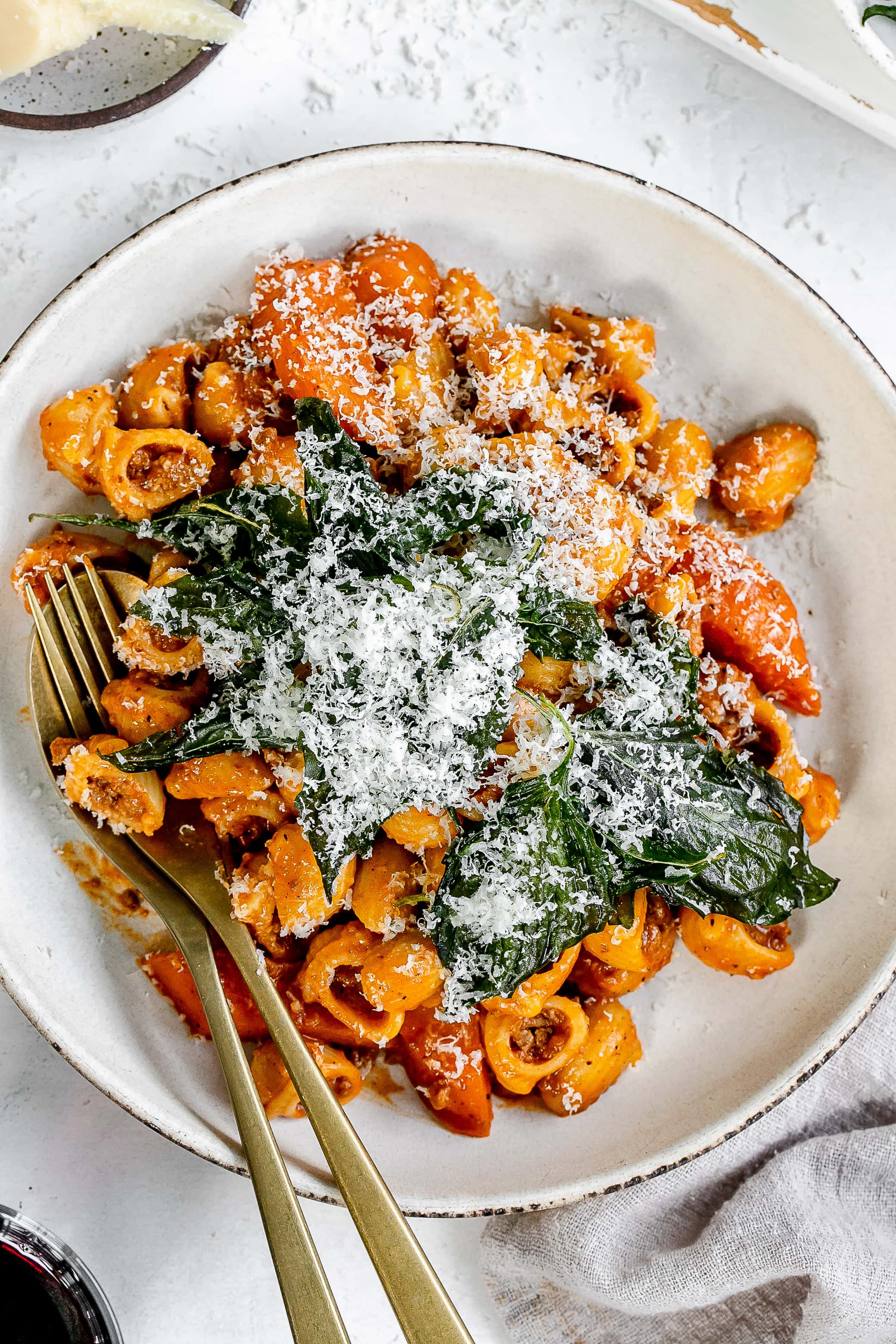 Thai bolognese on a plate topped with cheese and basil.