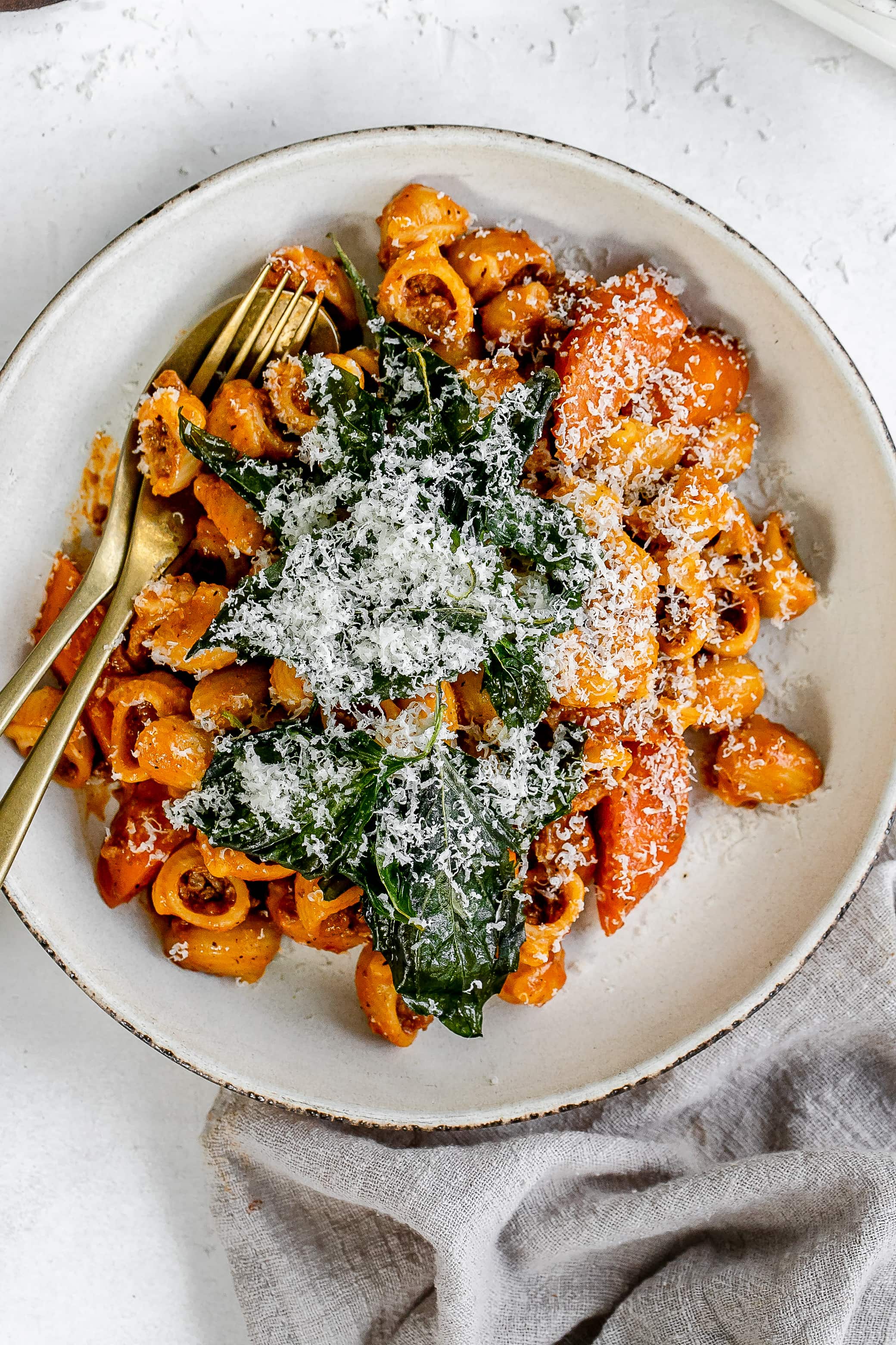 Thai bolognese on a plate topped with cheese and basil.