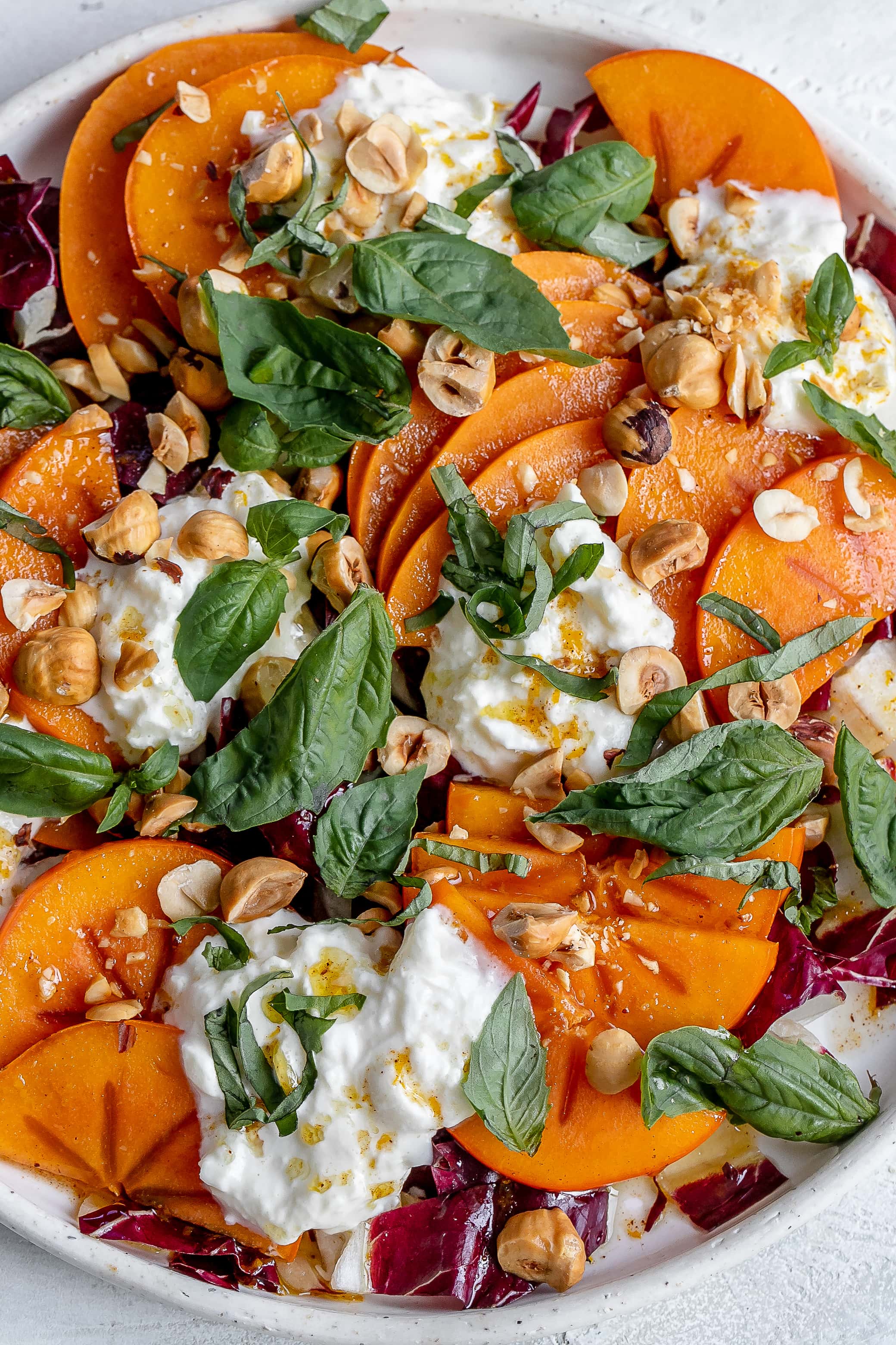 persimmon salad with burrata on a plate.