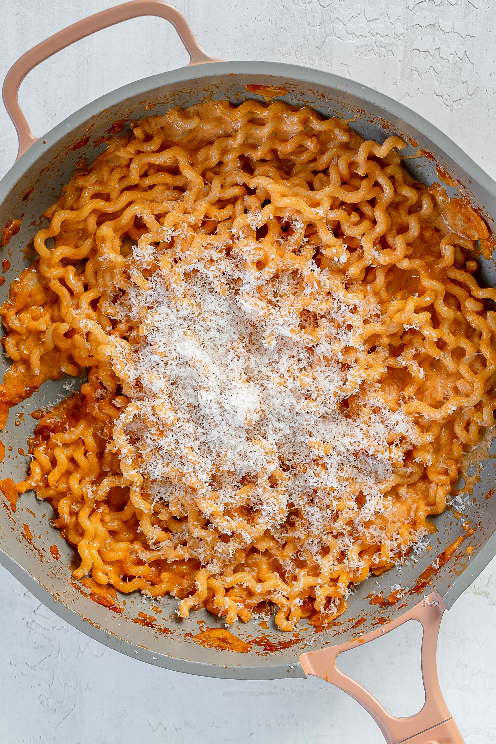 pasta in skillet with parmesan on top.