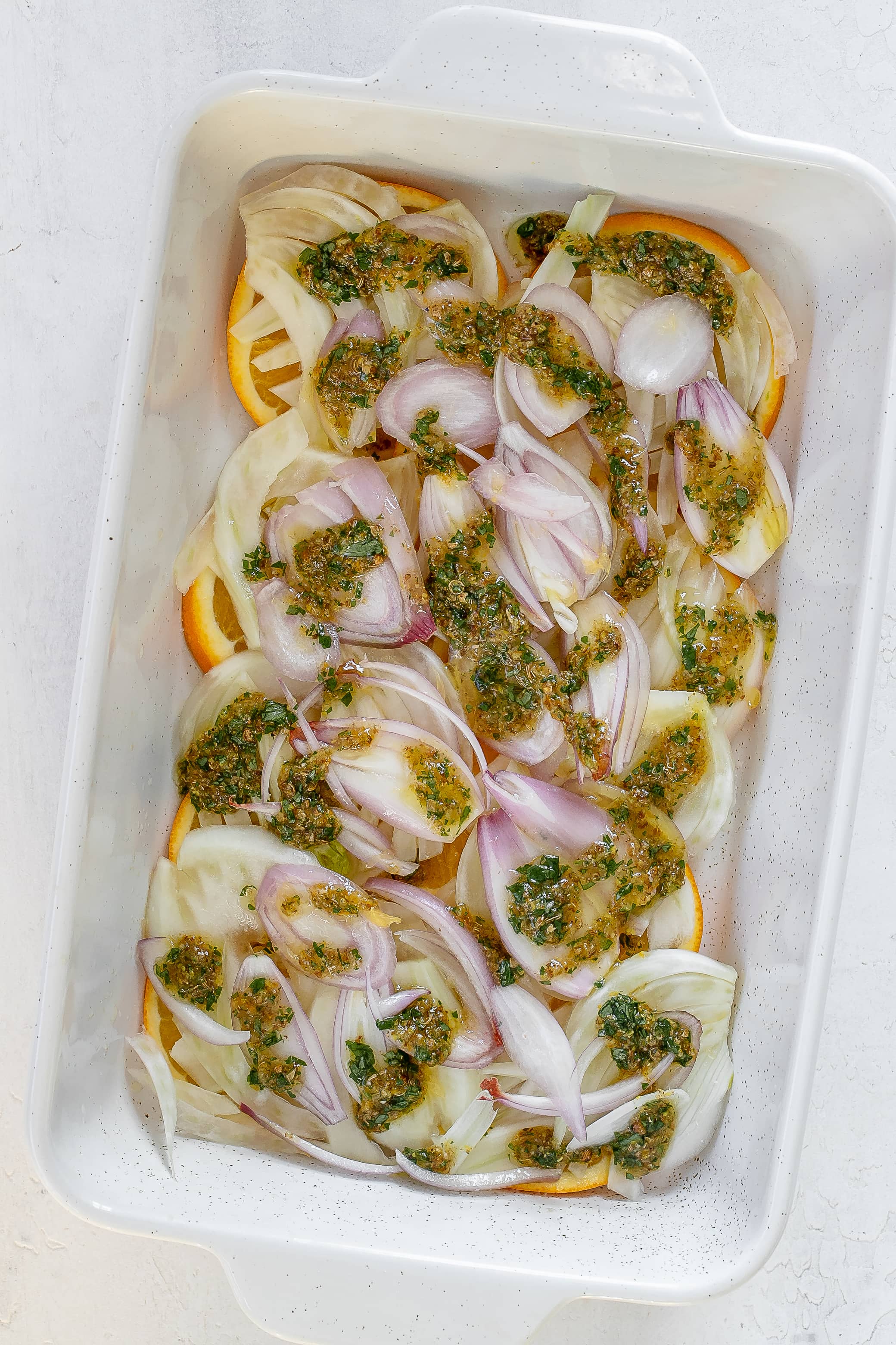 fennel and orange in baking dish with marinade.