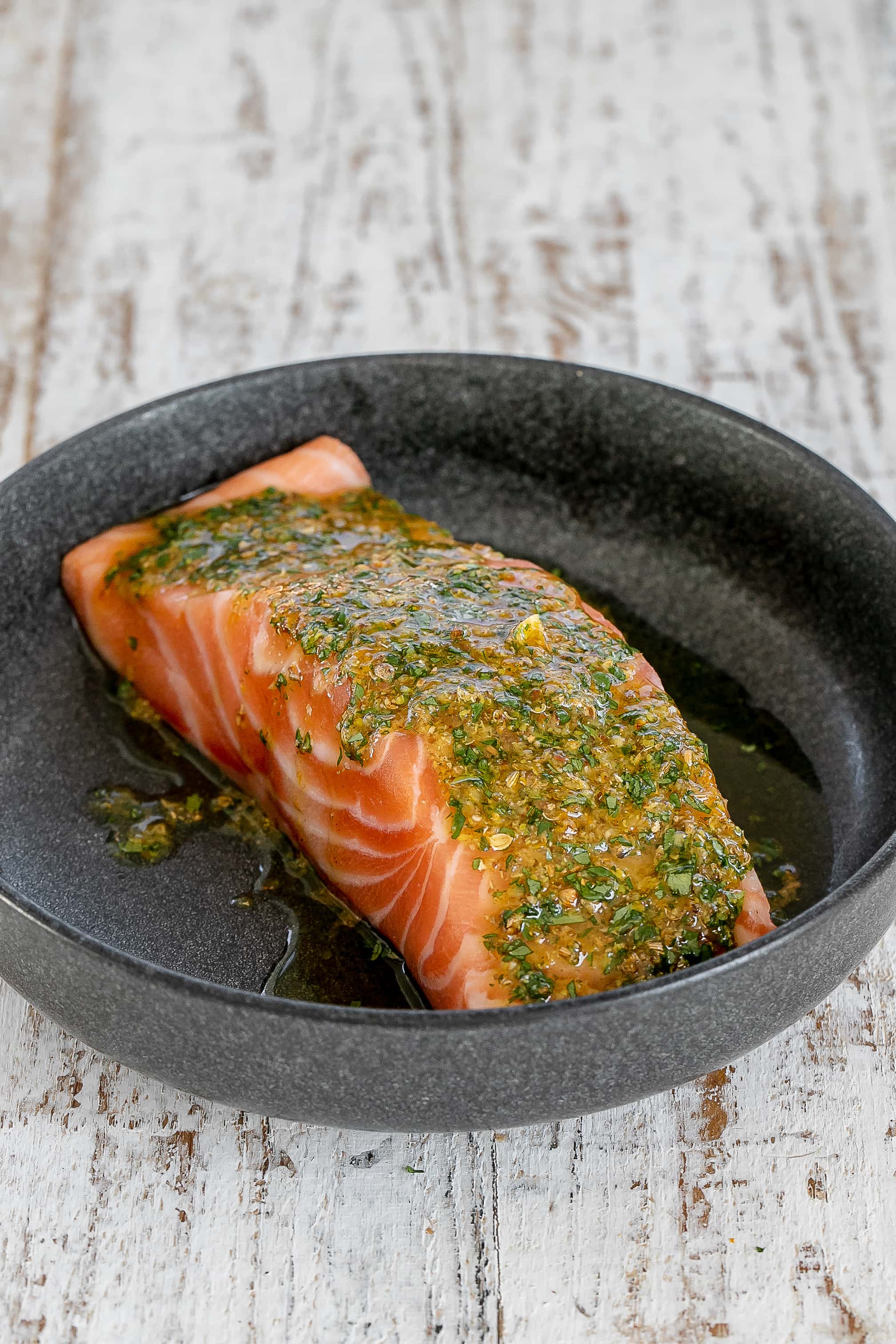 salmon in bowl with marinade on top.
