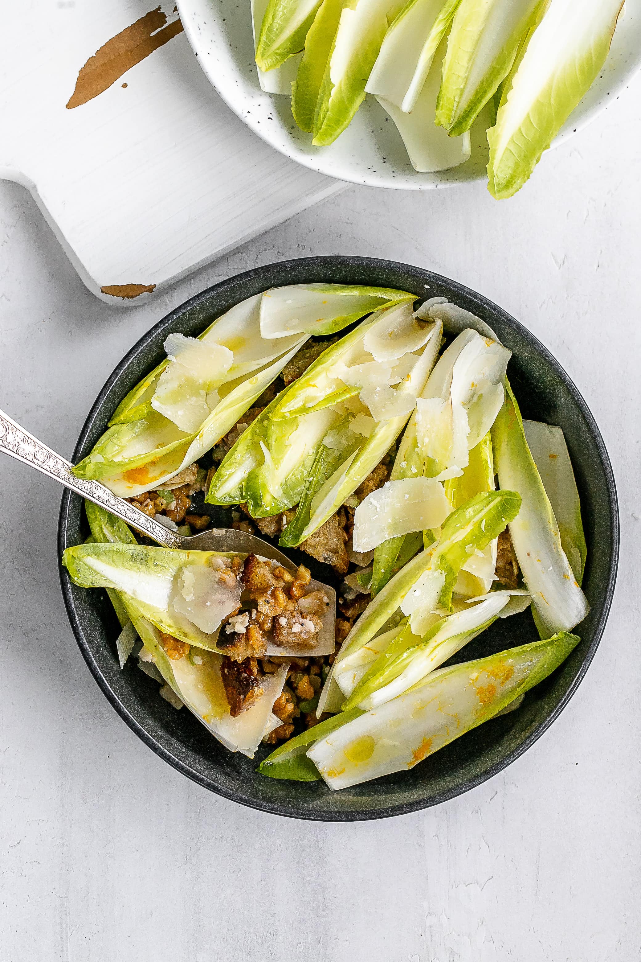 endive boats with filling underneath in bowl.