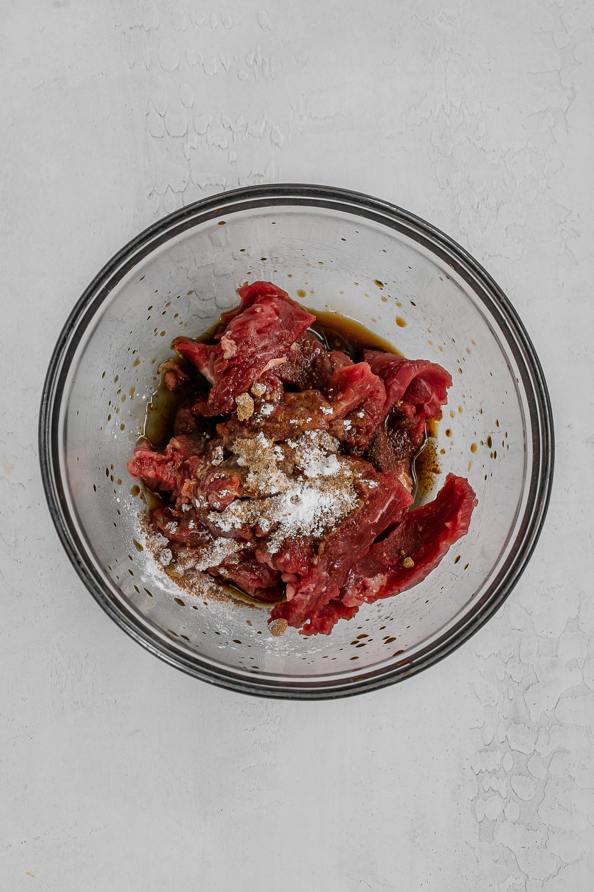 steak sliced in bowl with marinade ingredients. 