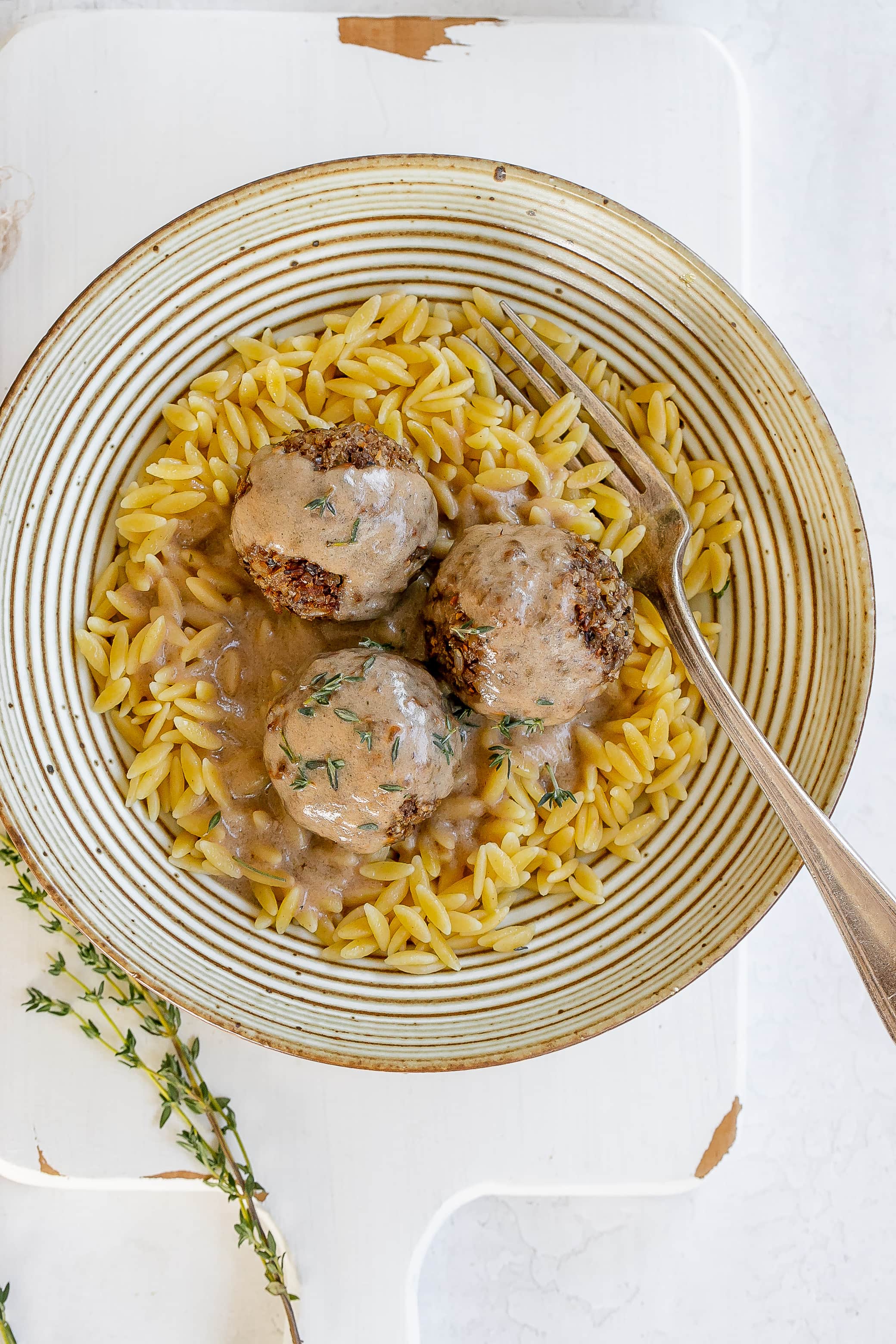 vegan mushroom meatballs in a bowl with orzo and sauce.