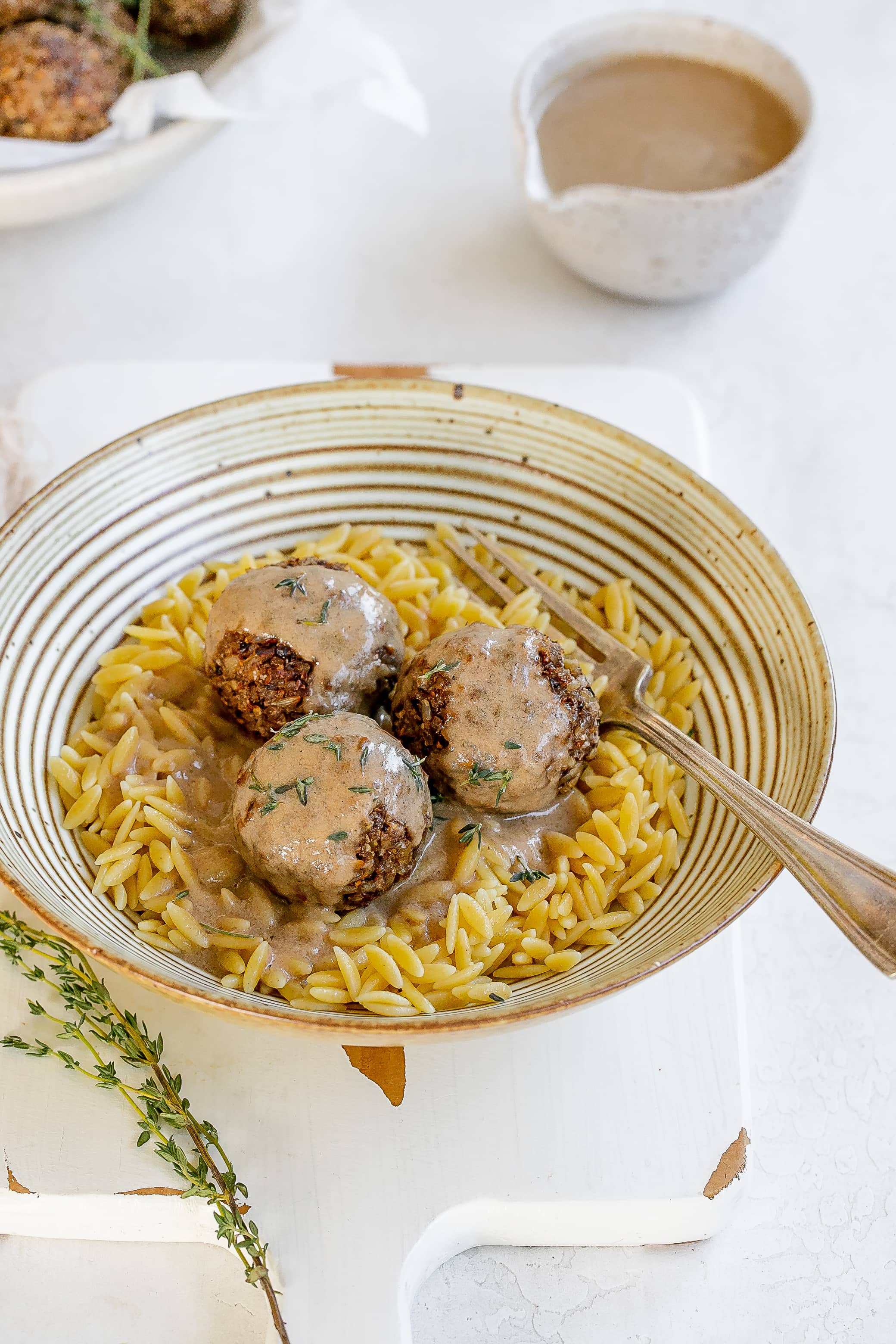 vegan mushroom meatballs in a bowl with orzo and sauce.