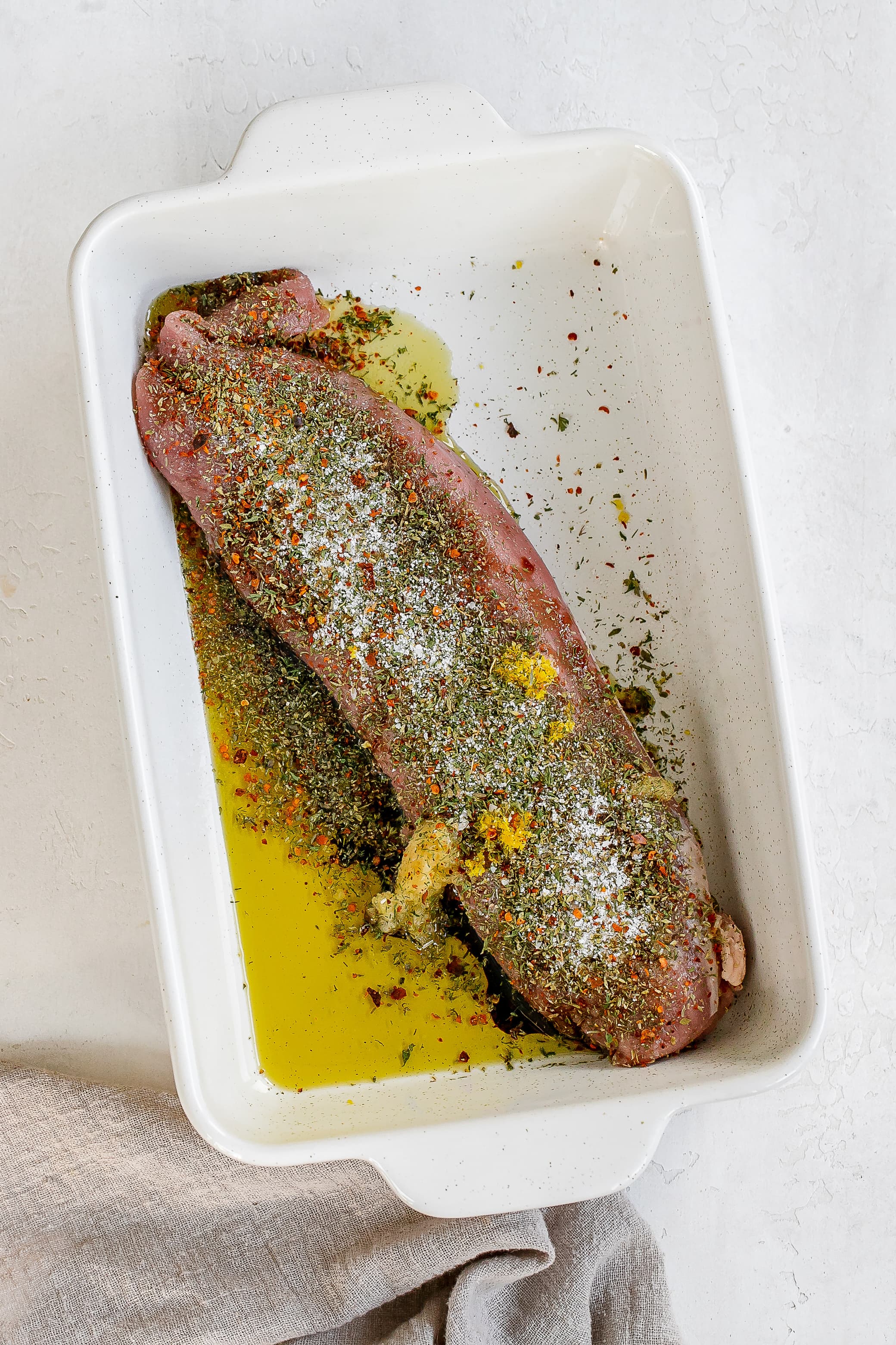 pork tenderloin with marinade ingredients in baking dish.