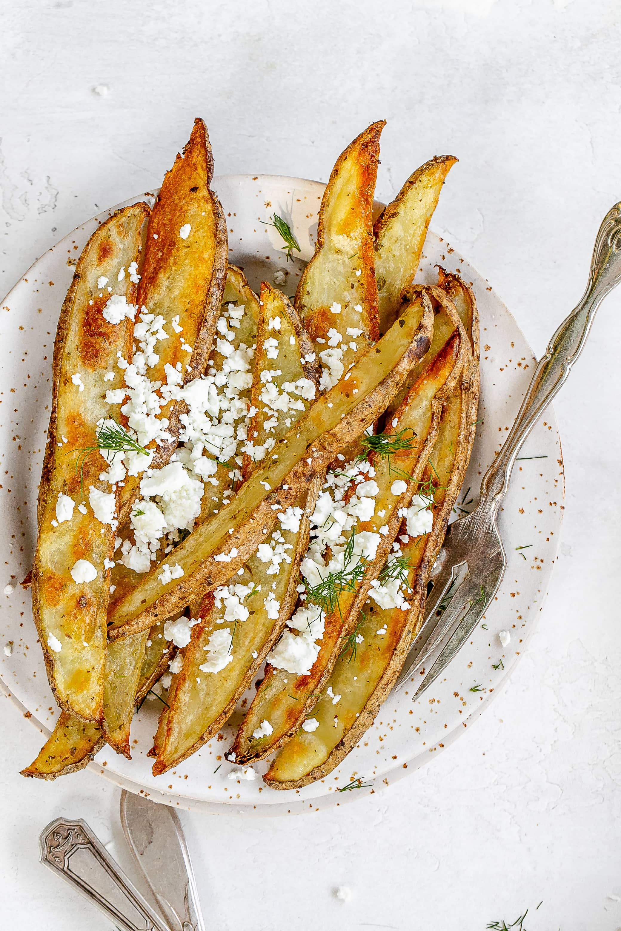 potato wedges on a plate with crumbled feta on top.