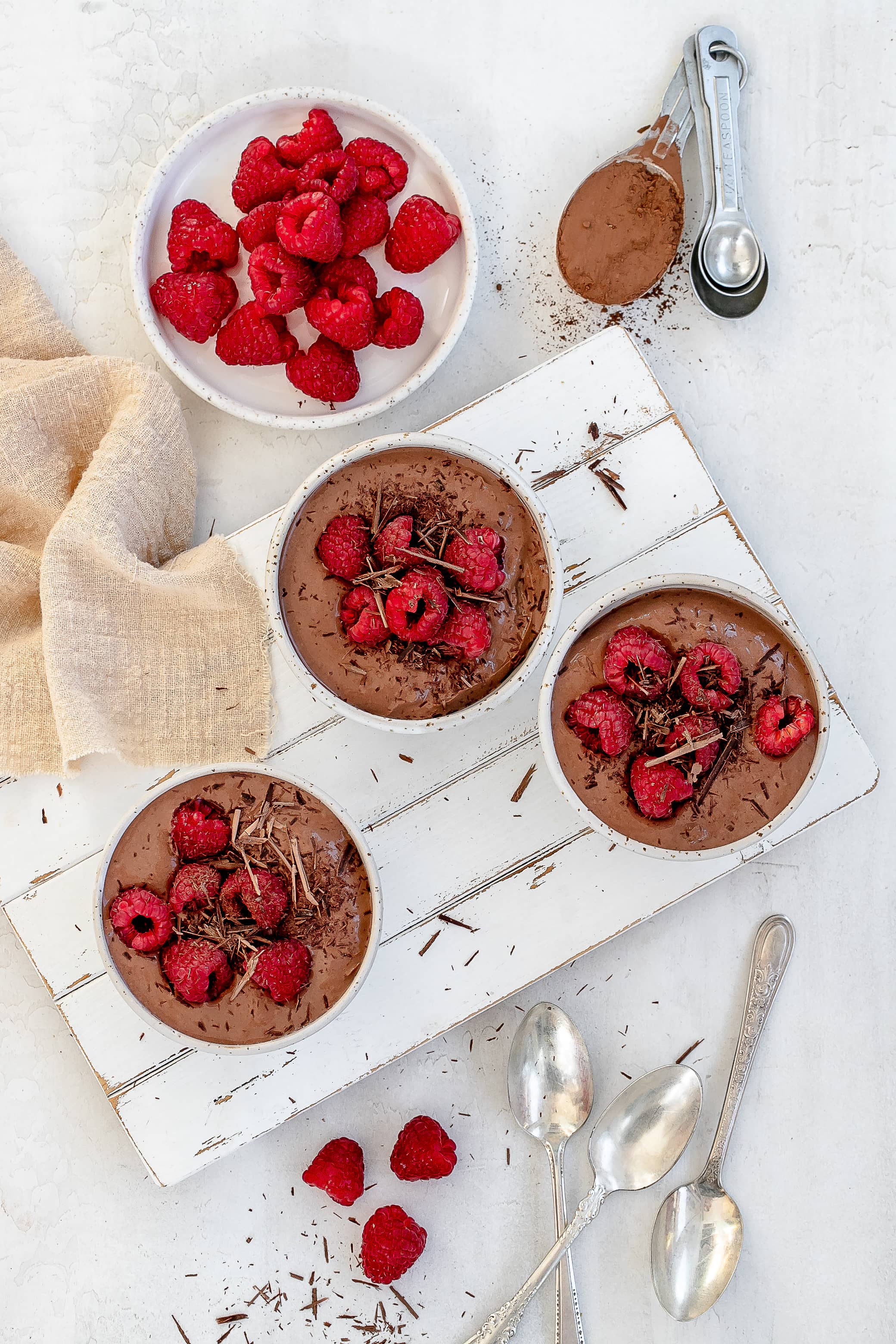 high protein Greek yogurt chocolate mousse in bowls with raspberries on top.