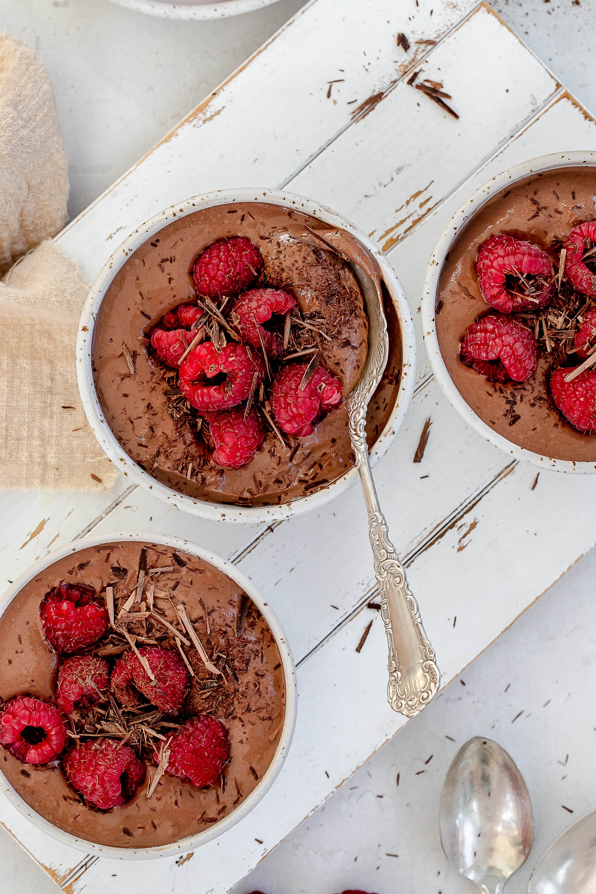 high protein Greek yogurt chocolate mousse in bowls with raspberries on top.
