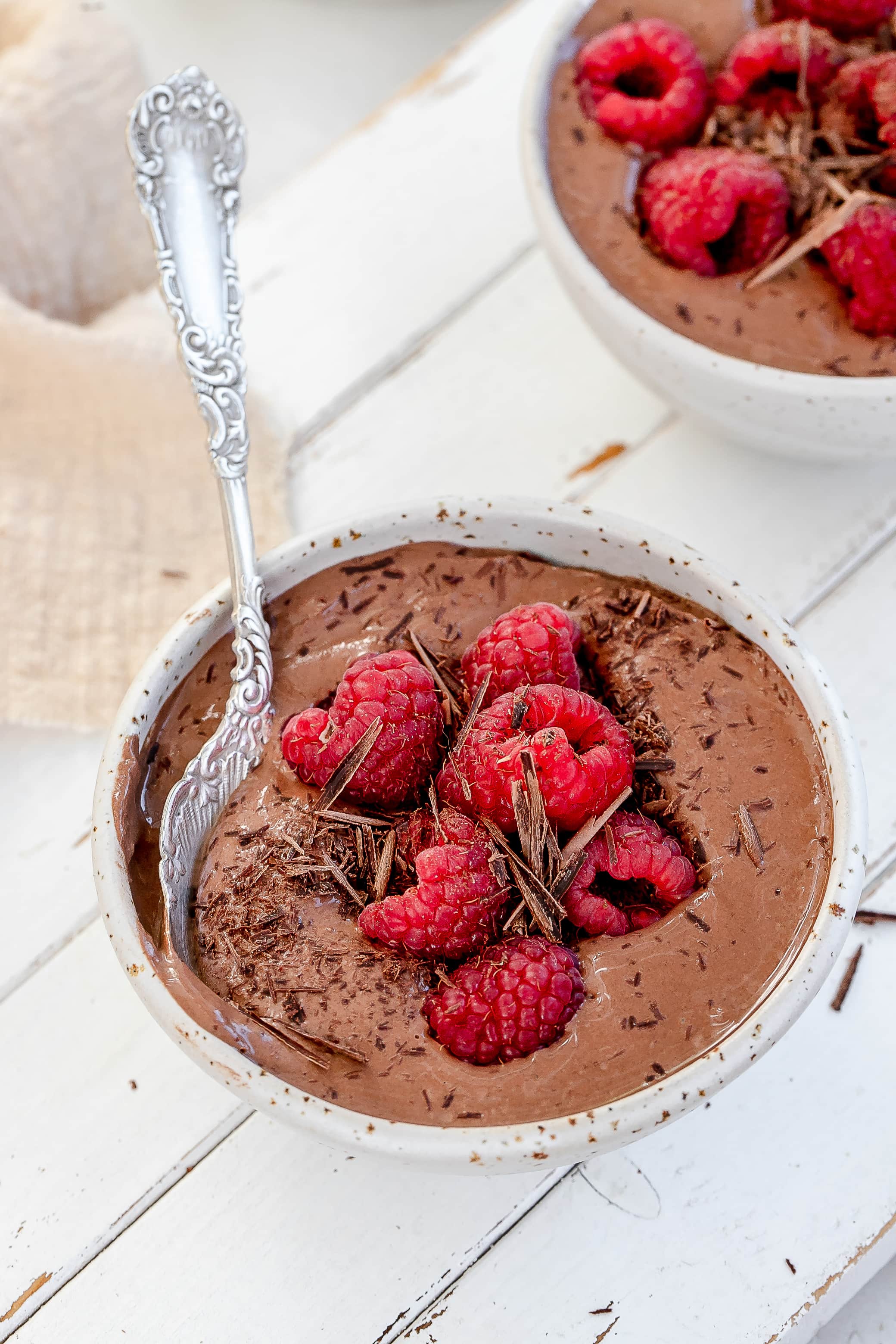 high protein Greek yogurt chocolate mousse in bowls with raspberries on top.