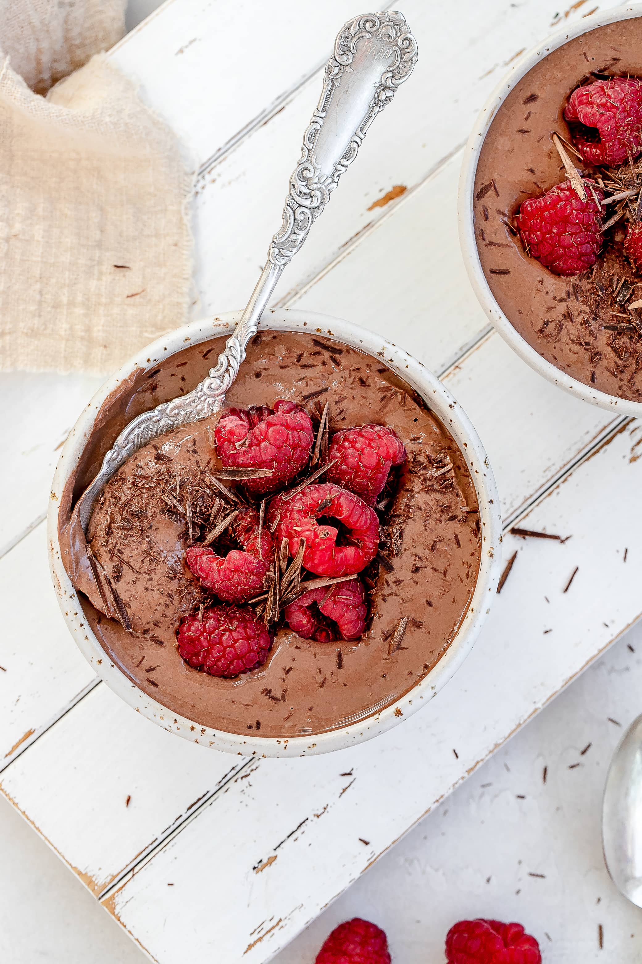high protein Greek yogurt chocolate mousse in bowls with raspberries on top.