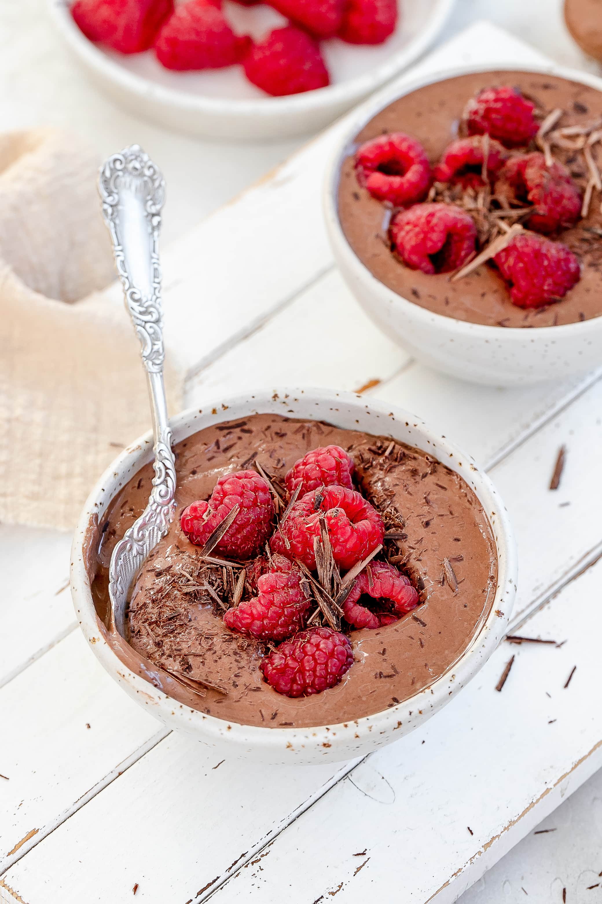 high protein Greek yogurt chocolate mousse in bowls with raspberries on top.