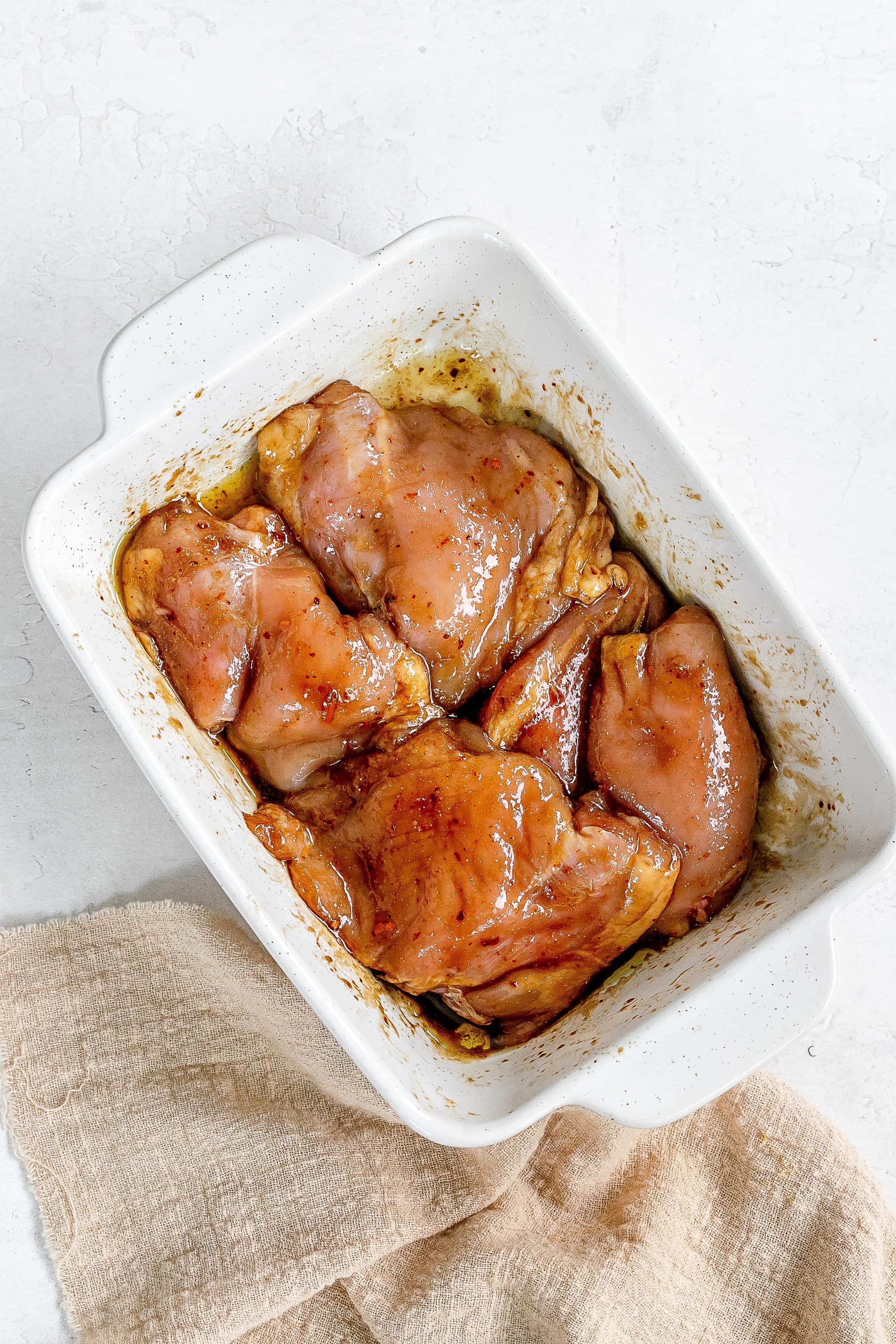 chicken thighs in baking dish with marinade.