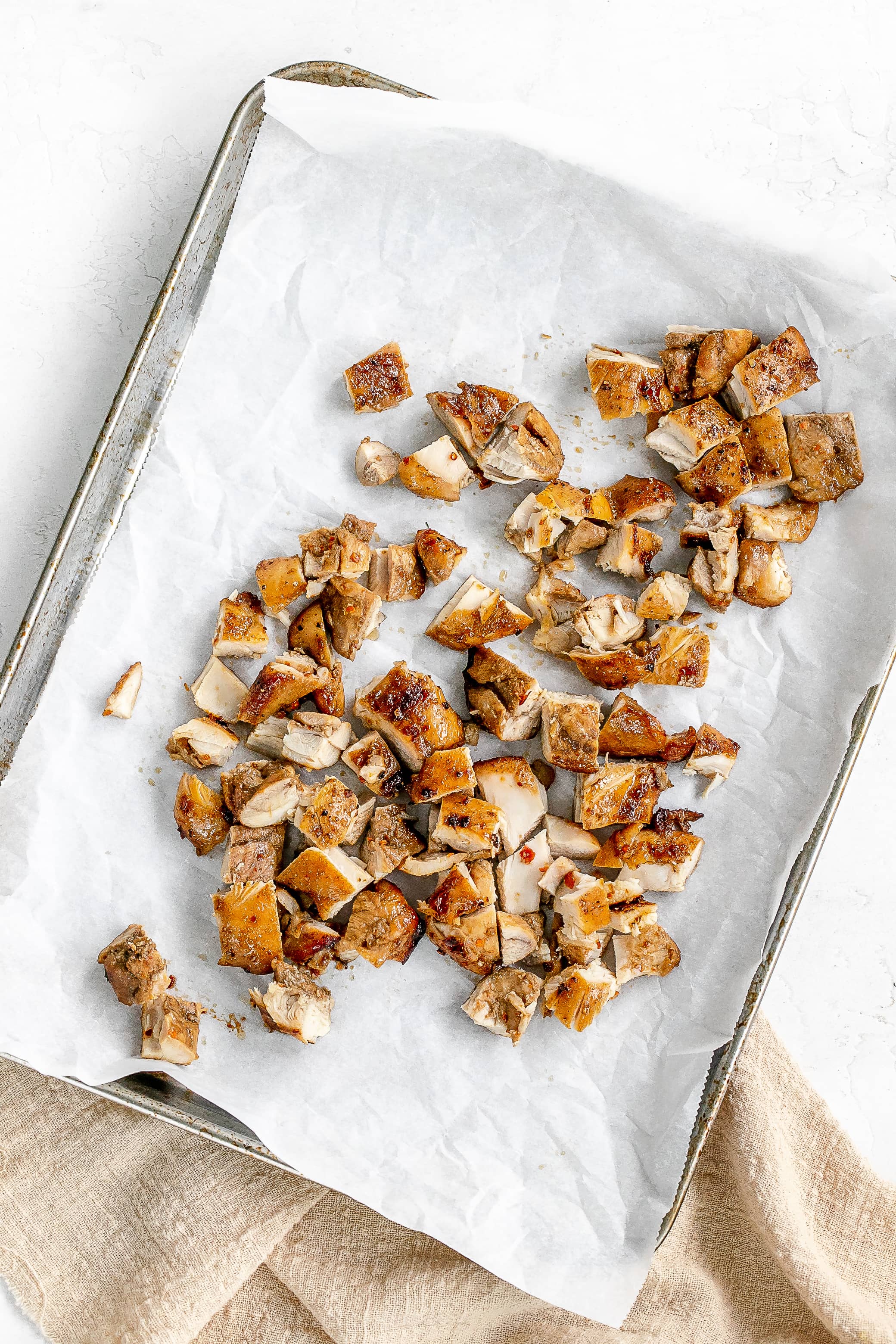 chicken chopped into bite sized pieces on baking sheet.