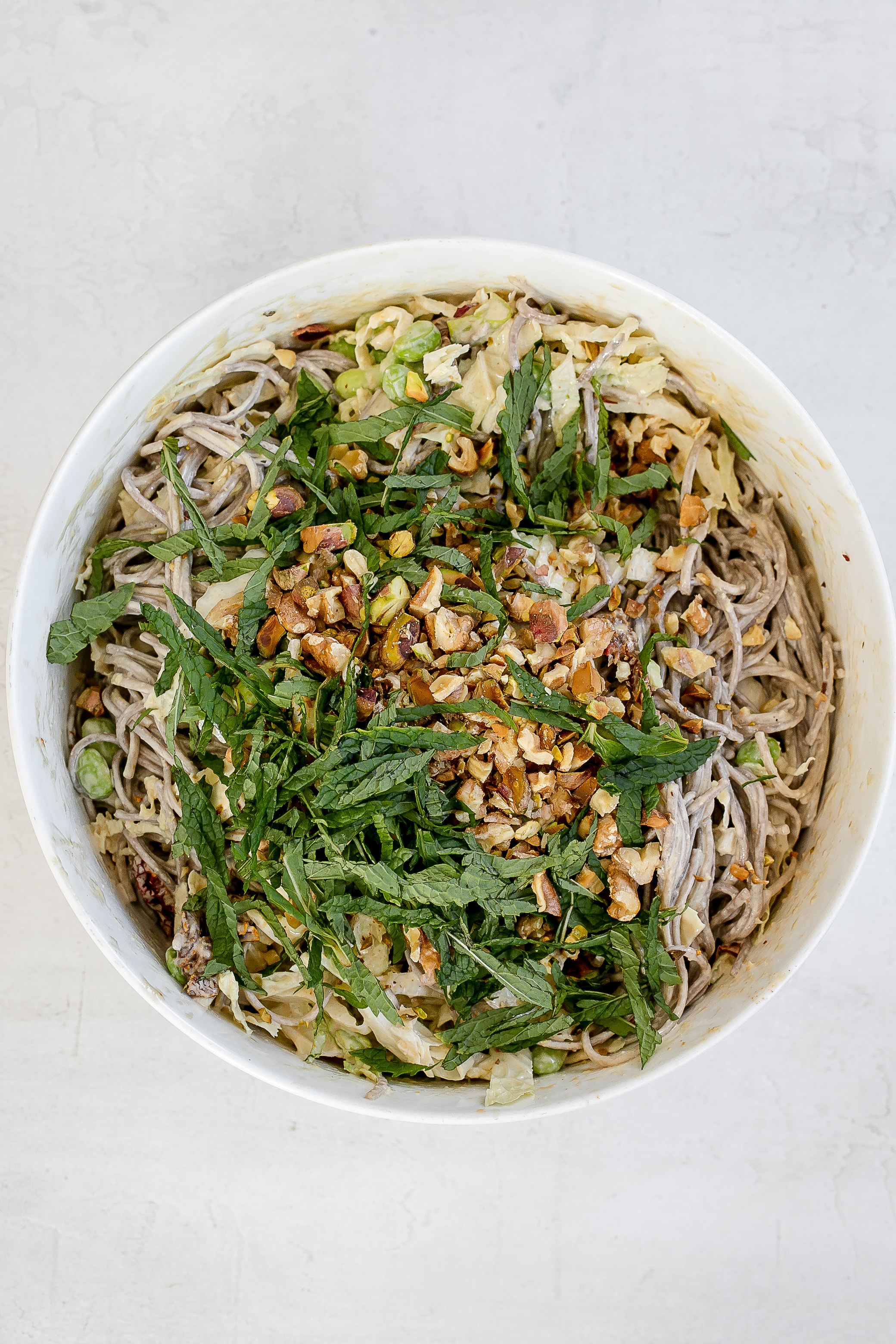 tahini sesame dressing added to noodles in large bowl. 