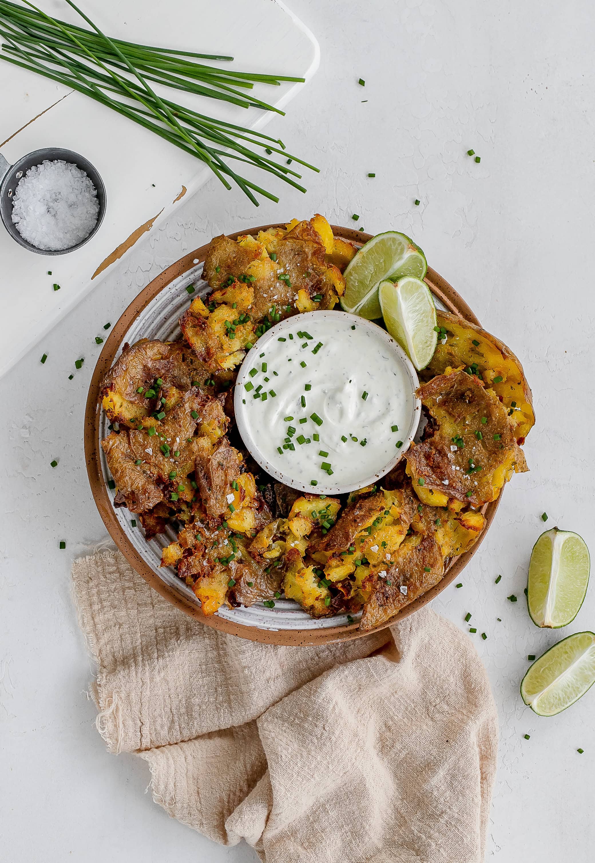 ranch smashed potatoes on a plate with dipping sauce. 