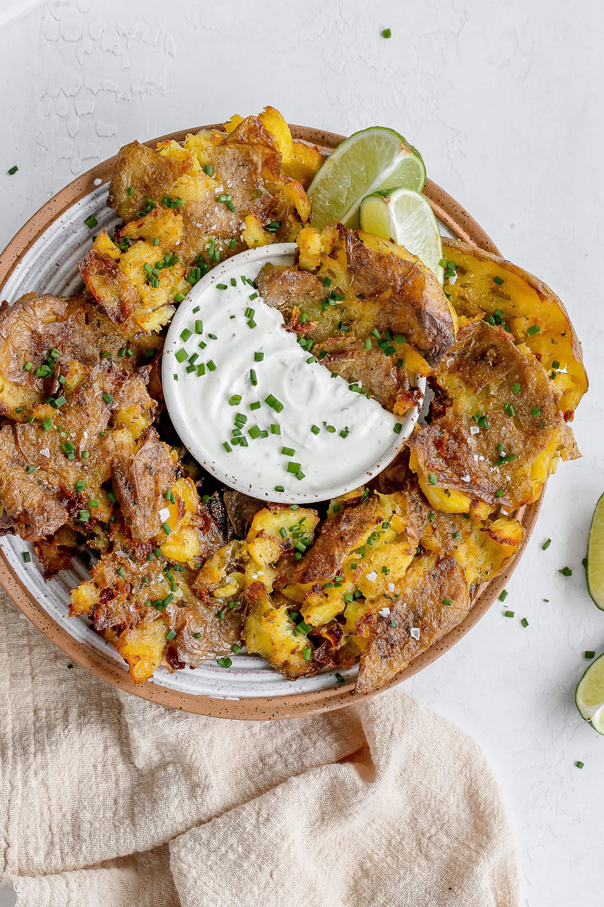 ranch smashed potatoes on a plate with dipping sauce. 